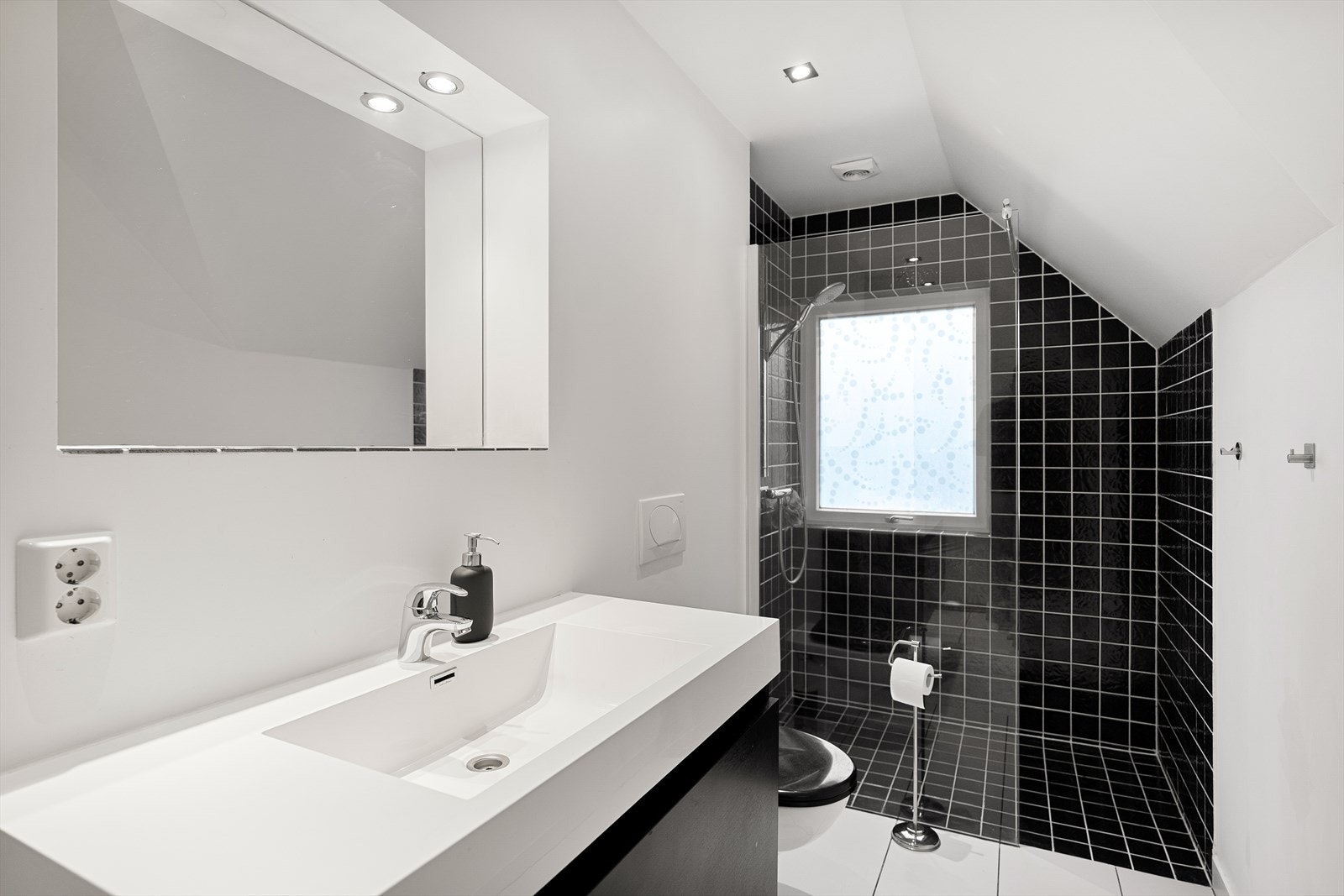 Stilrent og moderne baderom med elegante fliser og god belysning. Praktisk innredning med romslig dusj og vask. Galleribilde