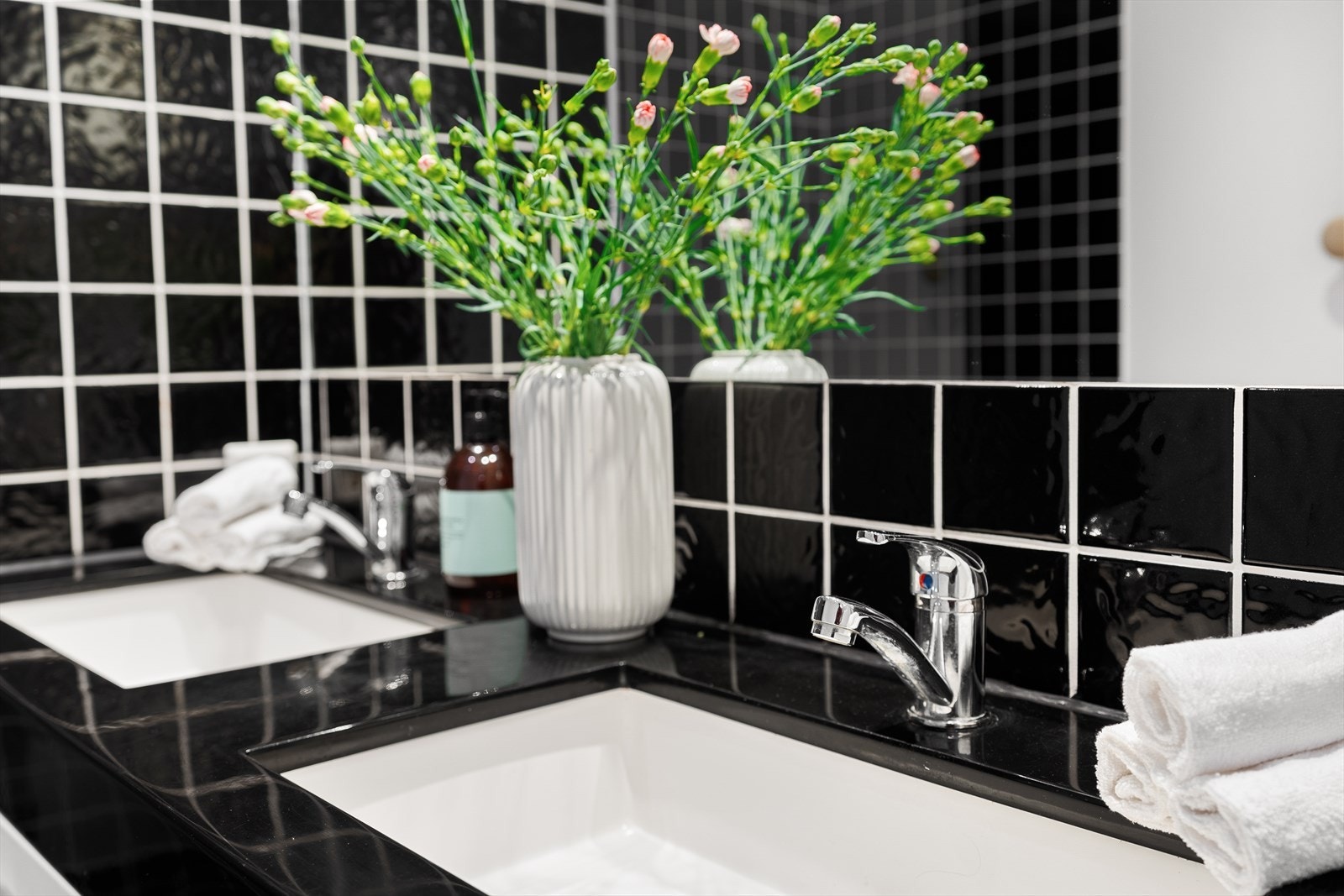 Moderne bad med dobbel vask og stilrene, svarte fliser. Elegant og innbydende design for et luksuriøst preg. Galleribilde