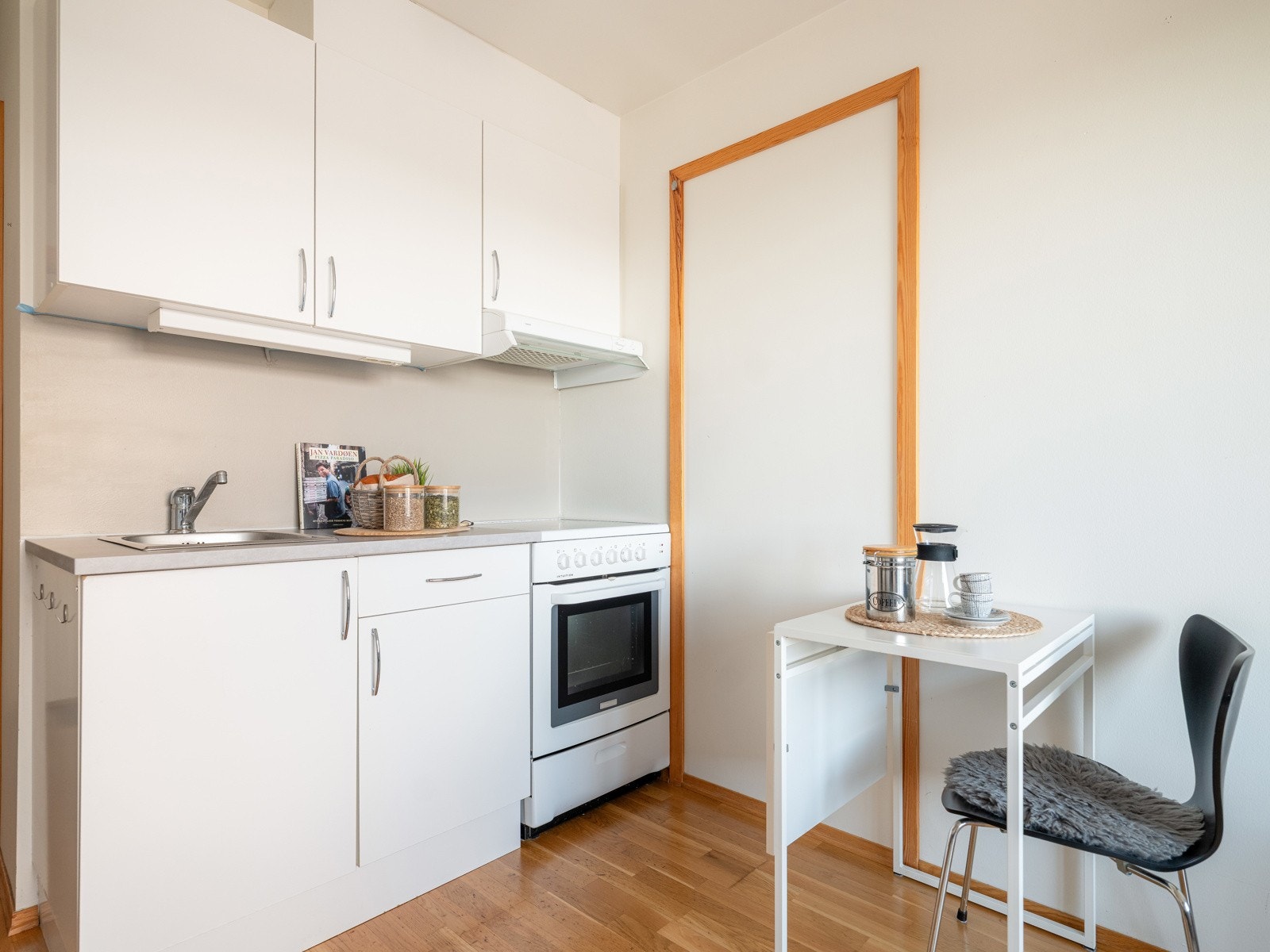 Enkel kjøkkeninnredning med oppbevaringsplass i både over- og underskap. Komfyr, kjøleskap og mikrobølgeovn medfølger i handelen. Galleribilde