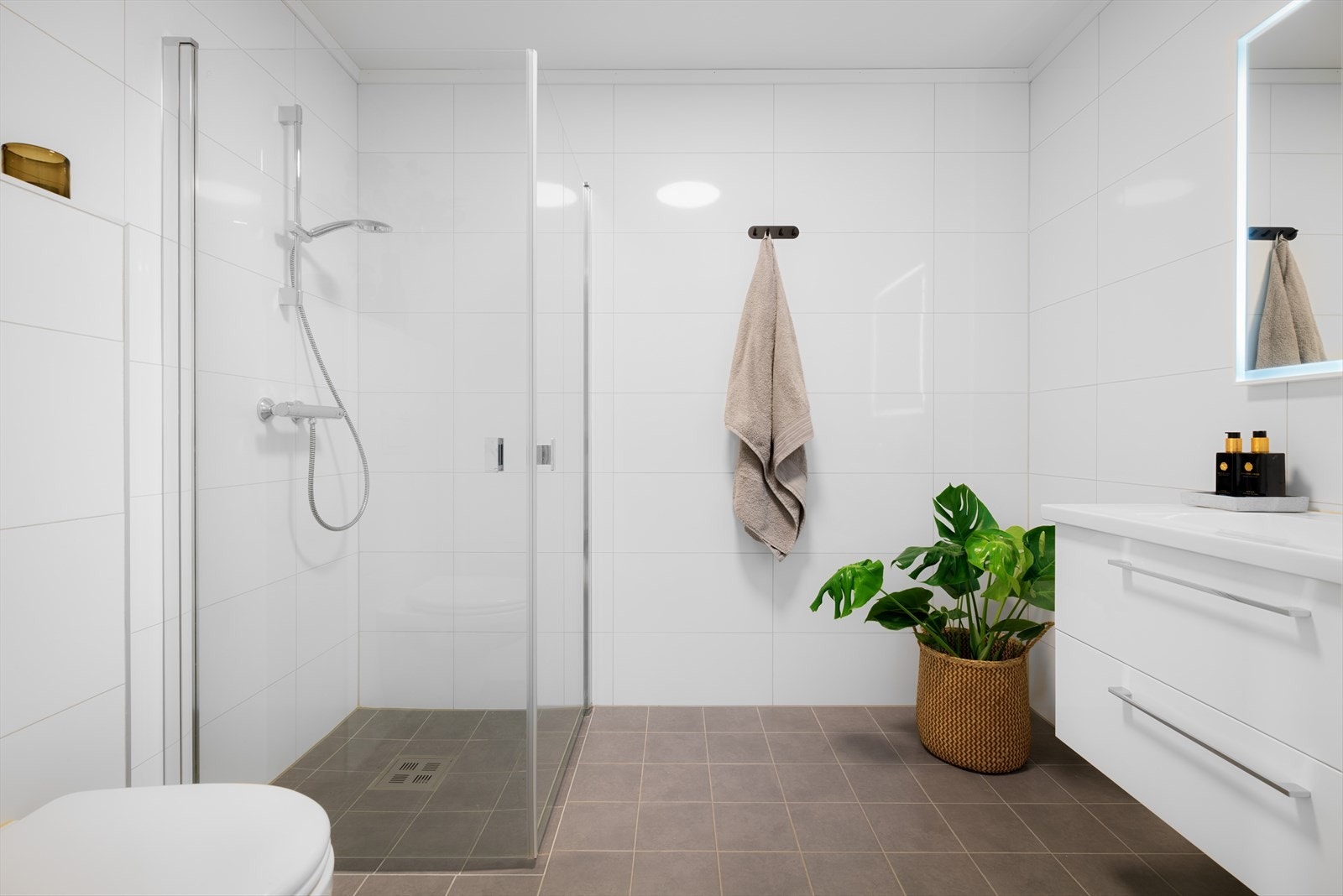 Boligen har to gode baderom. Her har vi et delikat, helfliset bad i første etasje med gulvvarme, dusj, toalett og servant. Galleribilde