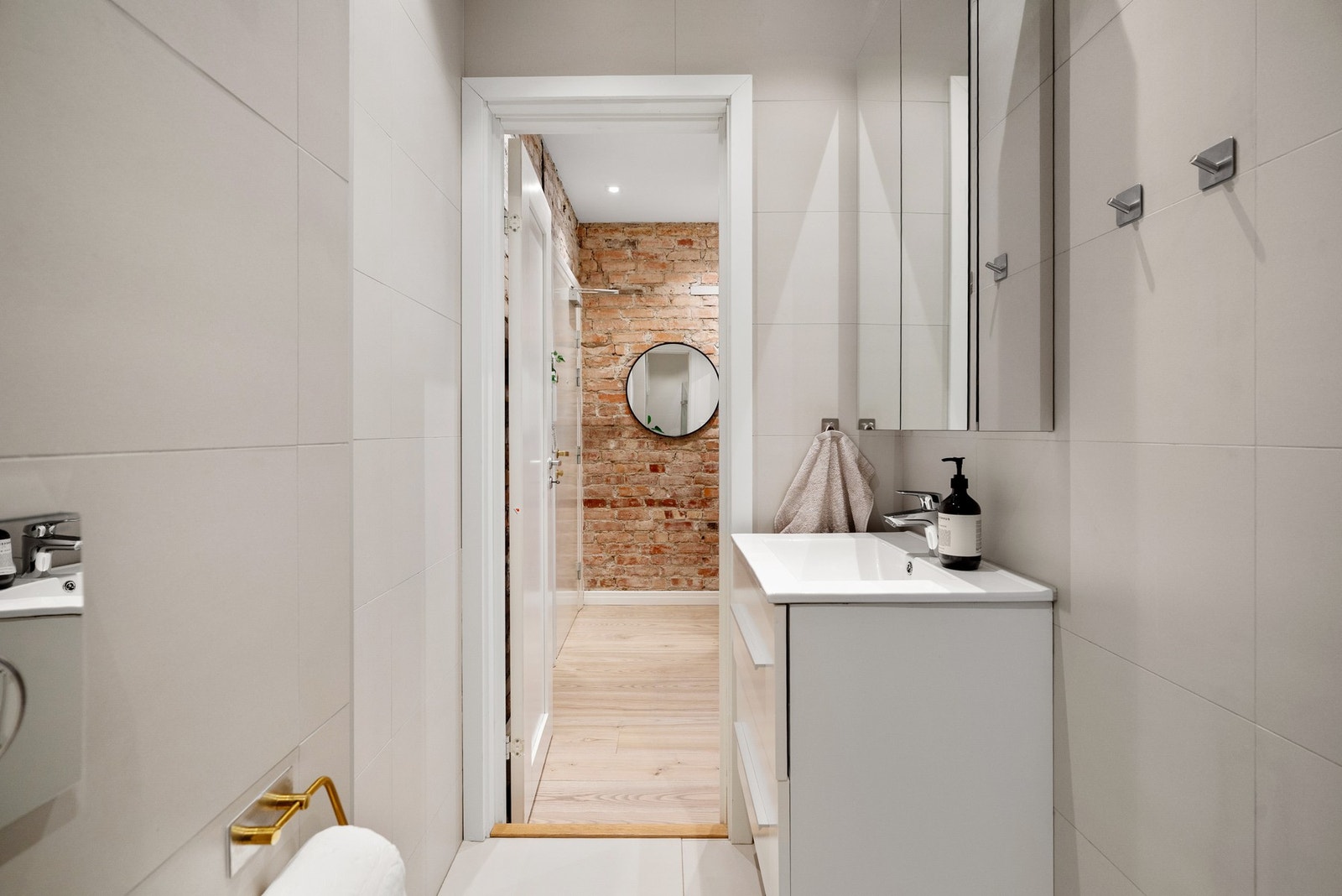 Baderomsinnredning med heldekkende servant med skuffer og vegghengt speilskap med oppbevaringsmuligheter. Galleribilde