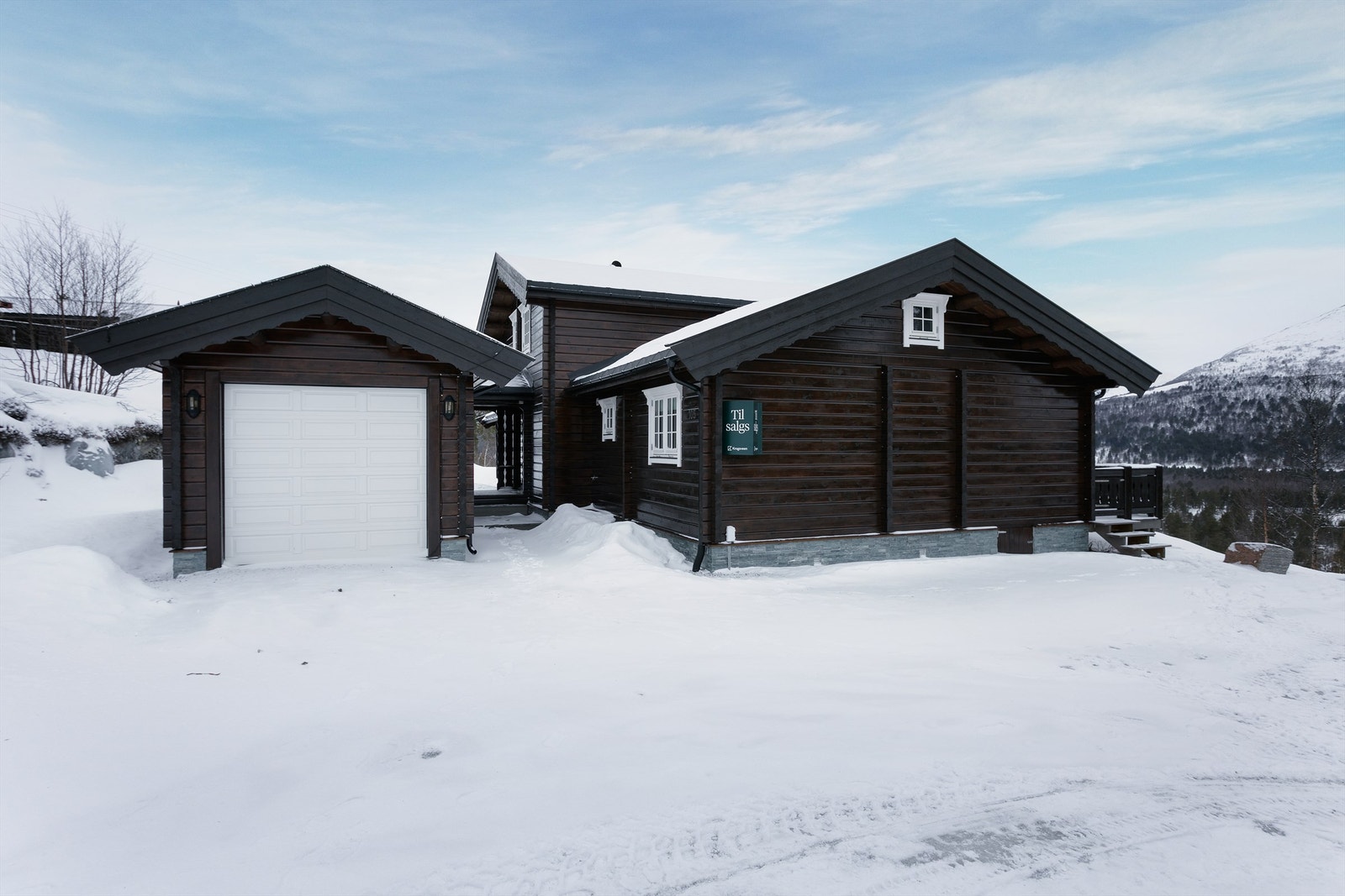 Adkomst, fasade og stort parkeringsareal i tilknytning til hytten Galleribilde