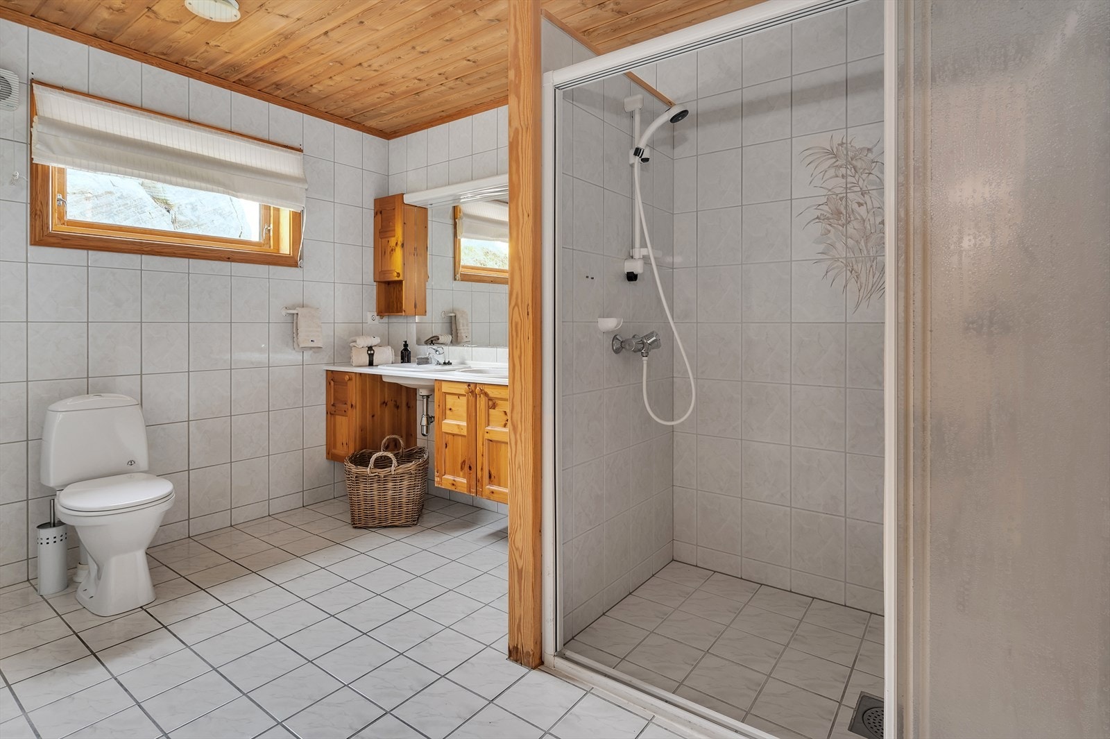 Badet byr på en romslig dusjnisje, servant med innredning, toalett, utslagsvask og opplegg til vaskemaskin. Galleribilde