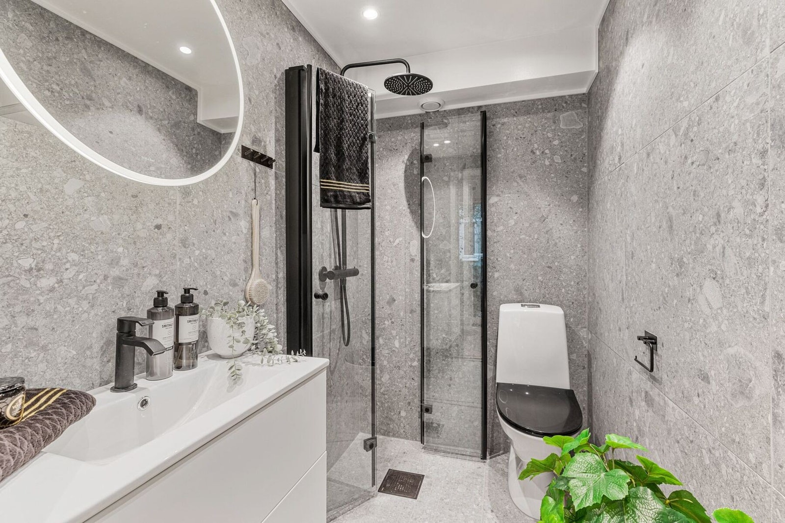 Speil på vegg fra Scala bad over servant med hyller og lys. Det er stikkontakt og ladeuttak i skapet. Gulvstående toalett. Galleribilde