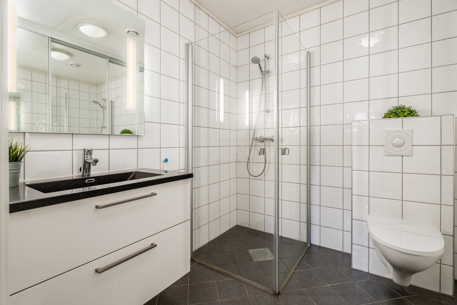 Lyst og pent, flislagt bad med vegghengt innrending og wc. Praktisk dusjhjørne med glassdører Galleribilde