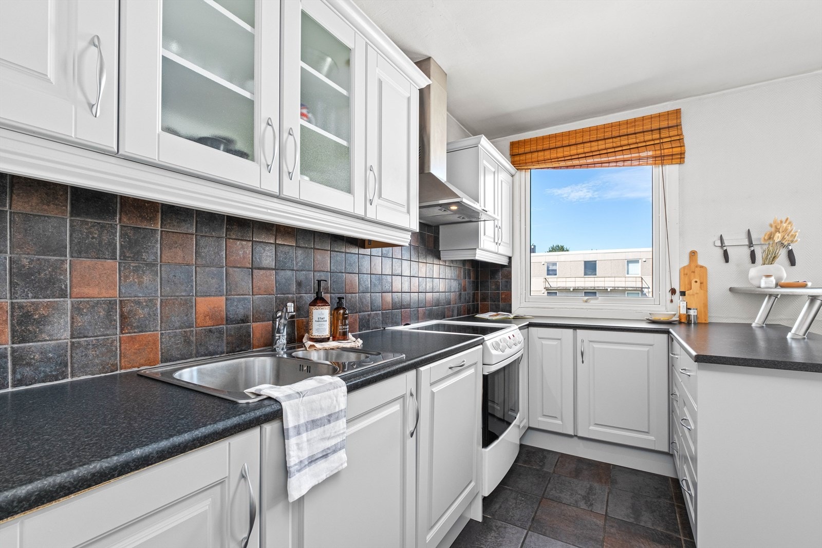 Flisene over kjøkkenbenken matcher gulvflisene. Galleribilde