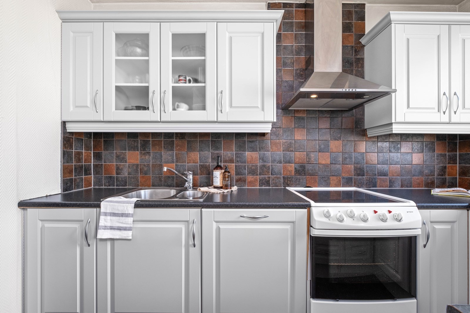 En dobbel kum er nedfelt i benkeplate av laminat og to av skapene har frostet glass. Galleribilde