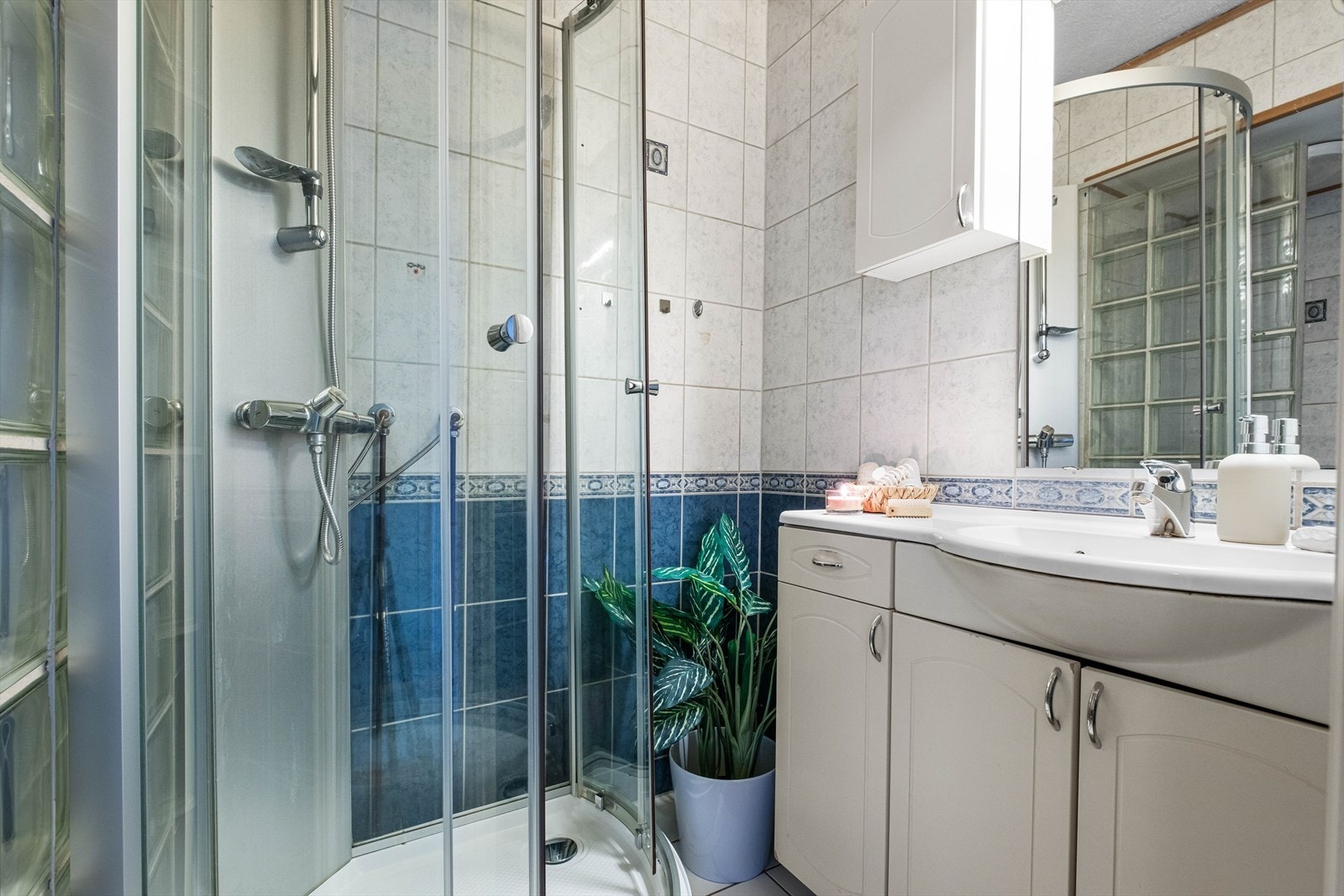 Baderommet har fliser, gulvvarme, dusjkabinett og hvit servantinnredning. Galleribilde