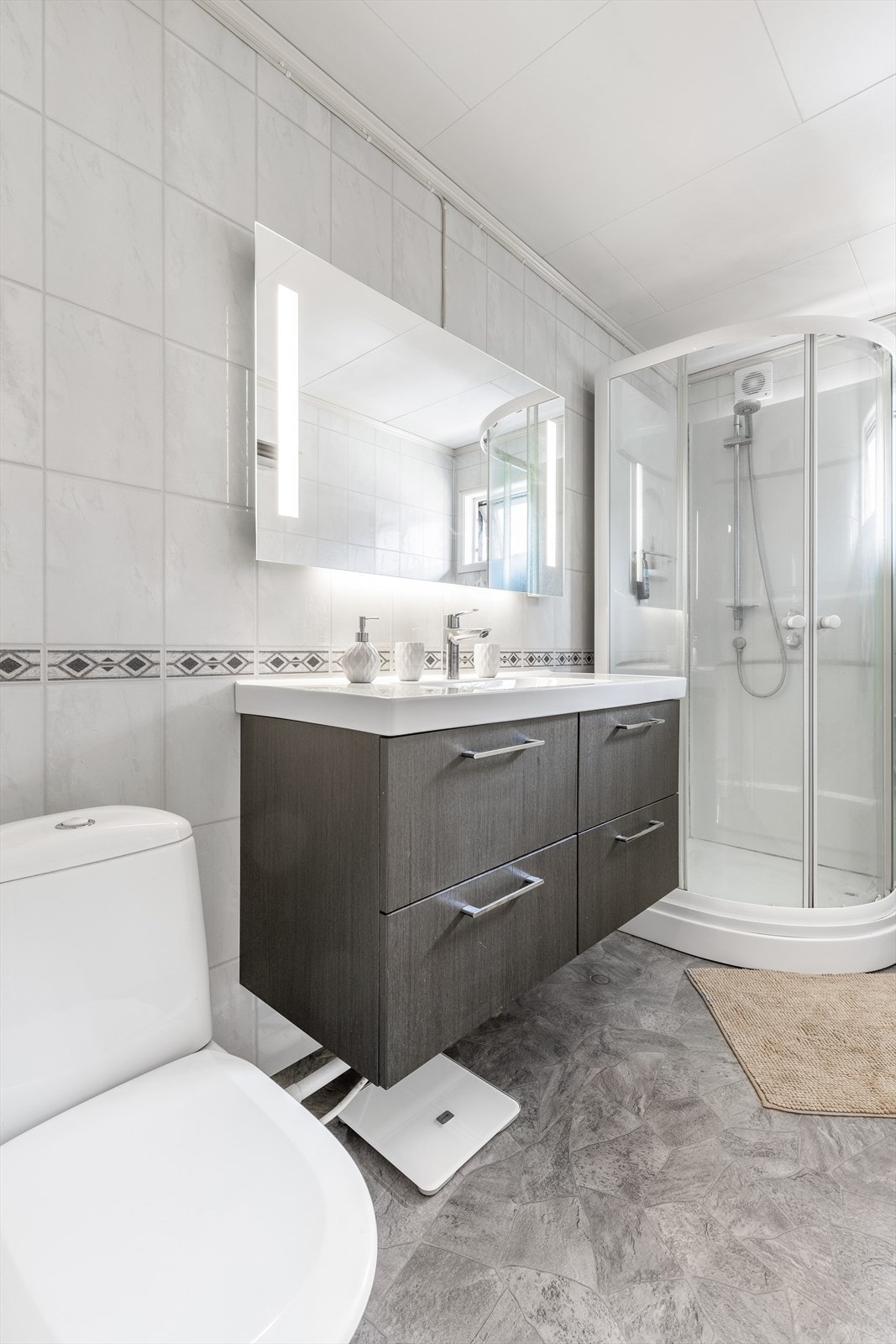 Baderom med nyere overflater og utstyr i boligens hovedetasje. Veggflatene er utført med våtromsplater og det er benyttet takessplater i tak / himlingen Galleribilde