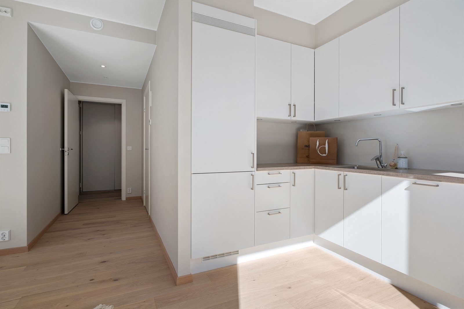 Leilighetens gode og smarte planløsning i kombinasjon med lekre farge- og materialvalg bidrar til en god atmosfære. Her får du beige detaljer på kjøkken, vegger malt i beige samt lekker 1-stavs eikeparkett. Galleribilde