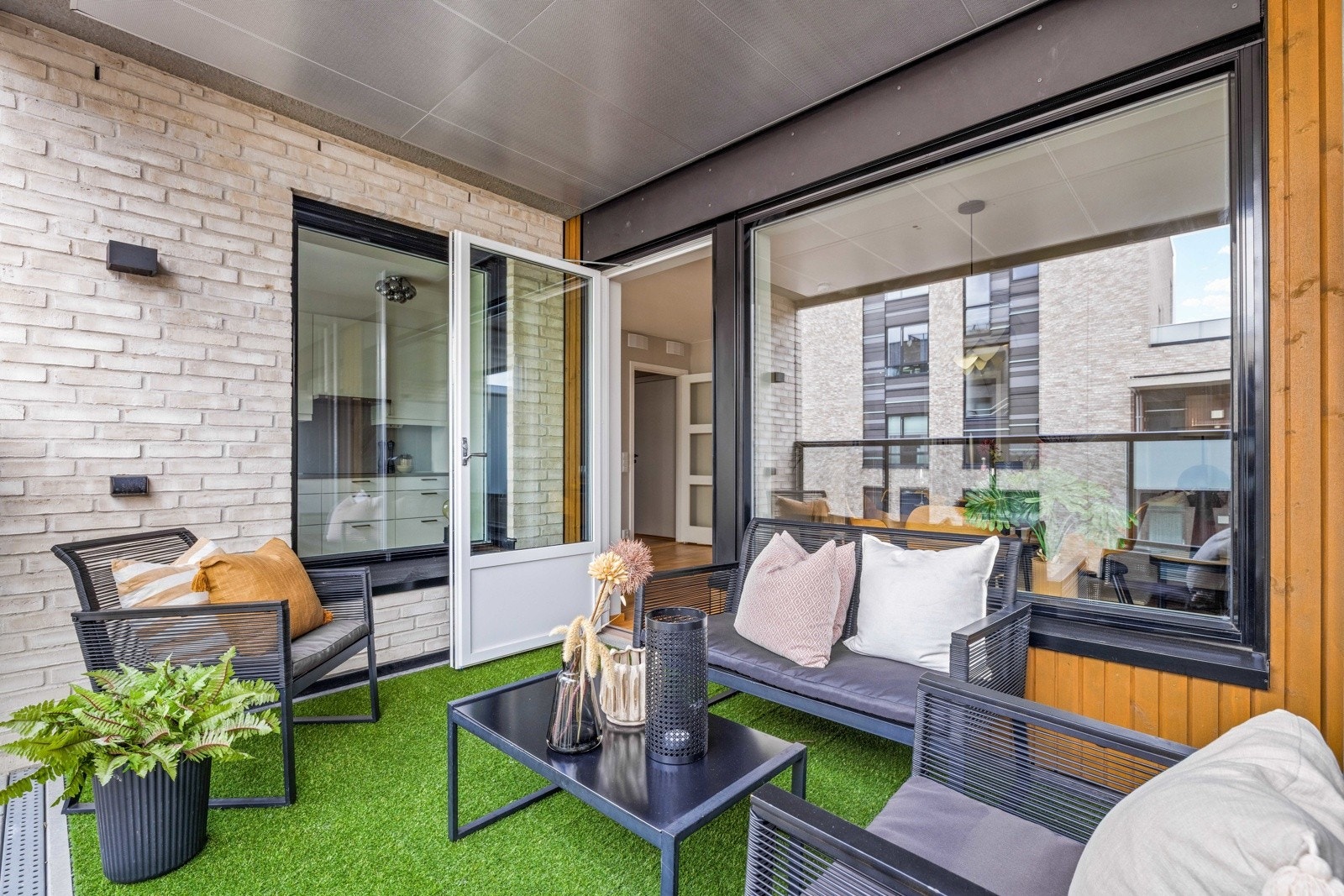 Uteplassen har teppe på betongdekke, skjermende levegg og rekkverk i glass. Utebelysning på vegg og stikkontakt. Galleribilde