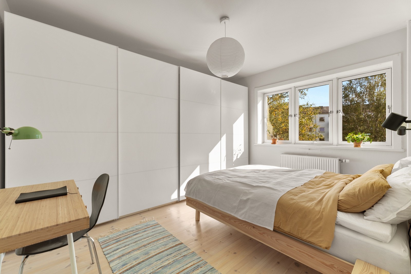 Leiligheten har et romslig soverom med et stort vindu som gir naturlig lys og gode muligheter for lufting. Fremfor sengen er det montert en stor skyvedørsgarderobe. Galleribilde