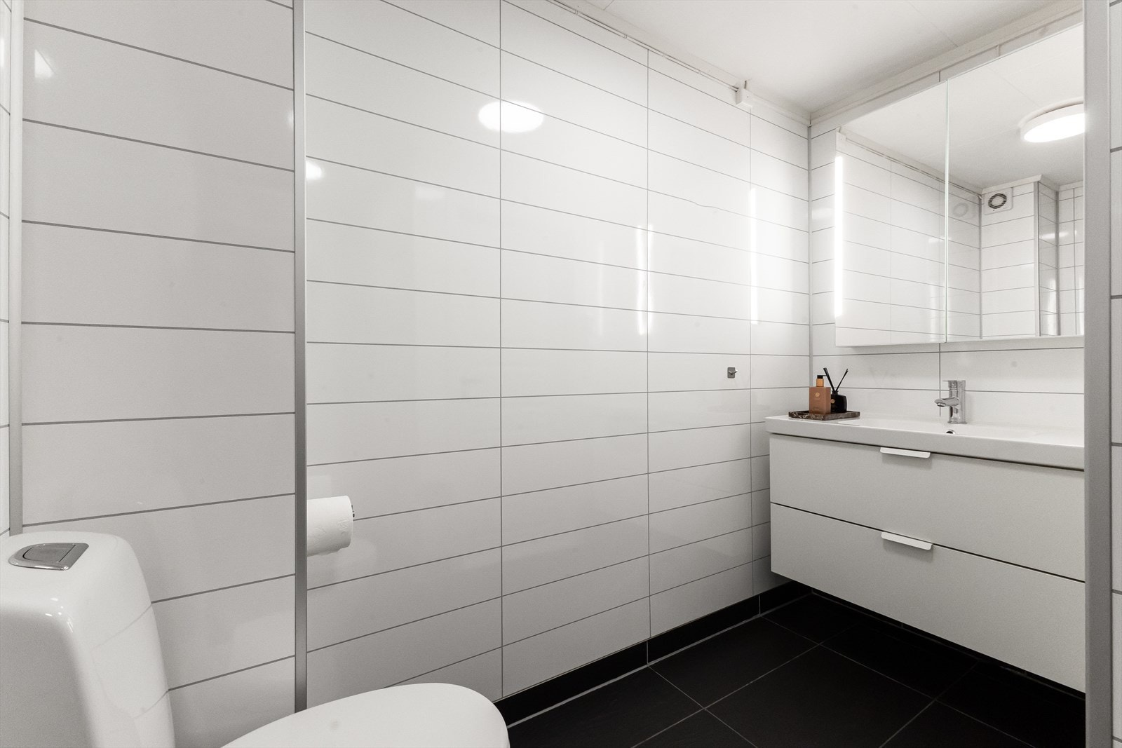 Fliser på gulv med varmekabler og innredning med speilskap og store skuffer. Galleribilde