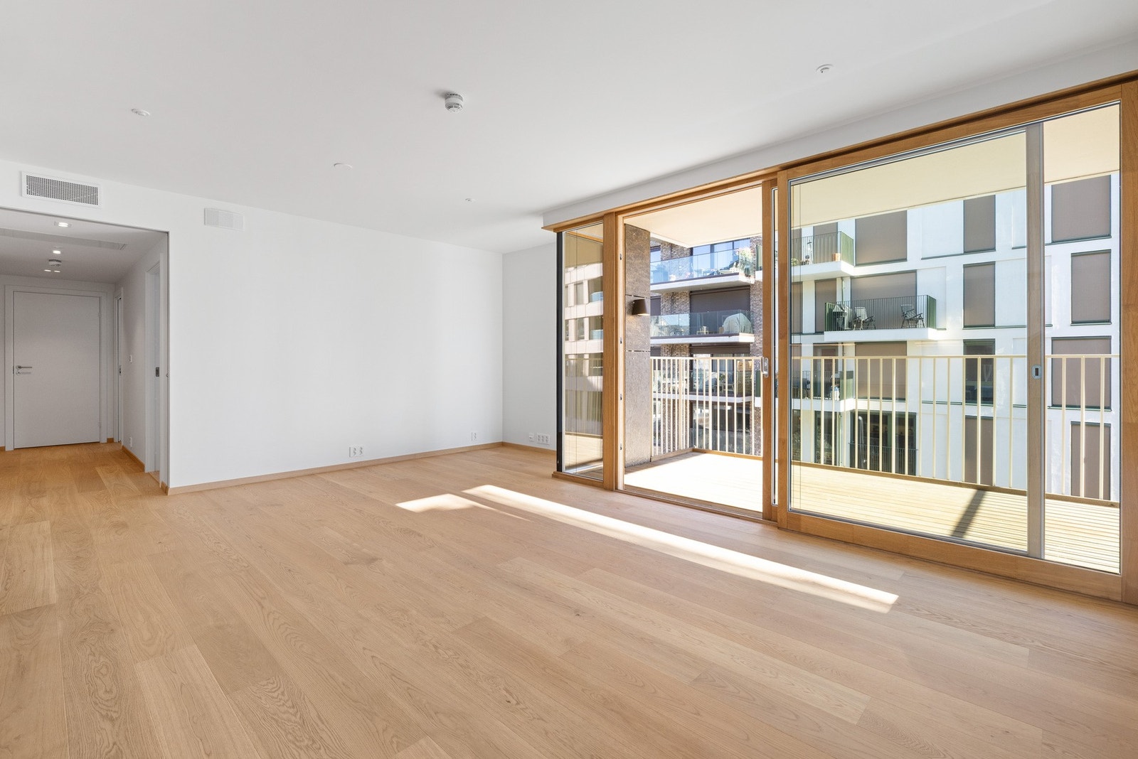 Luftig stue med skyvedører i eik som går fra gulv til tak. Galleribilde