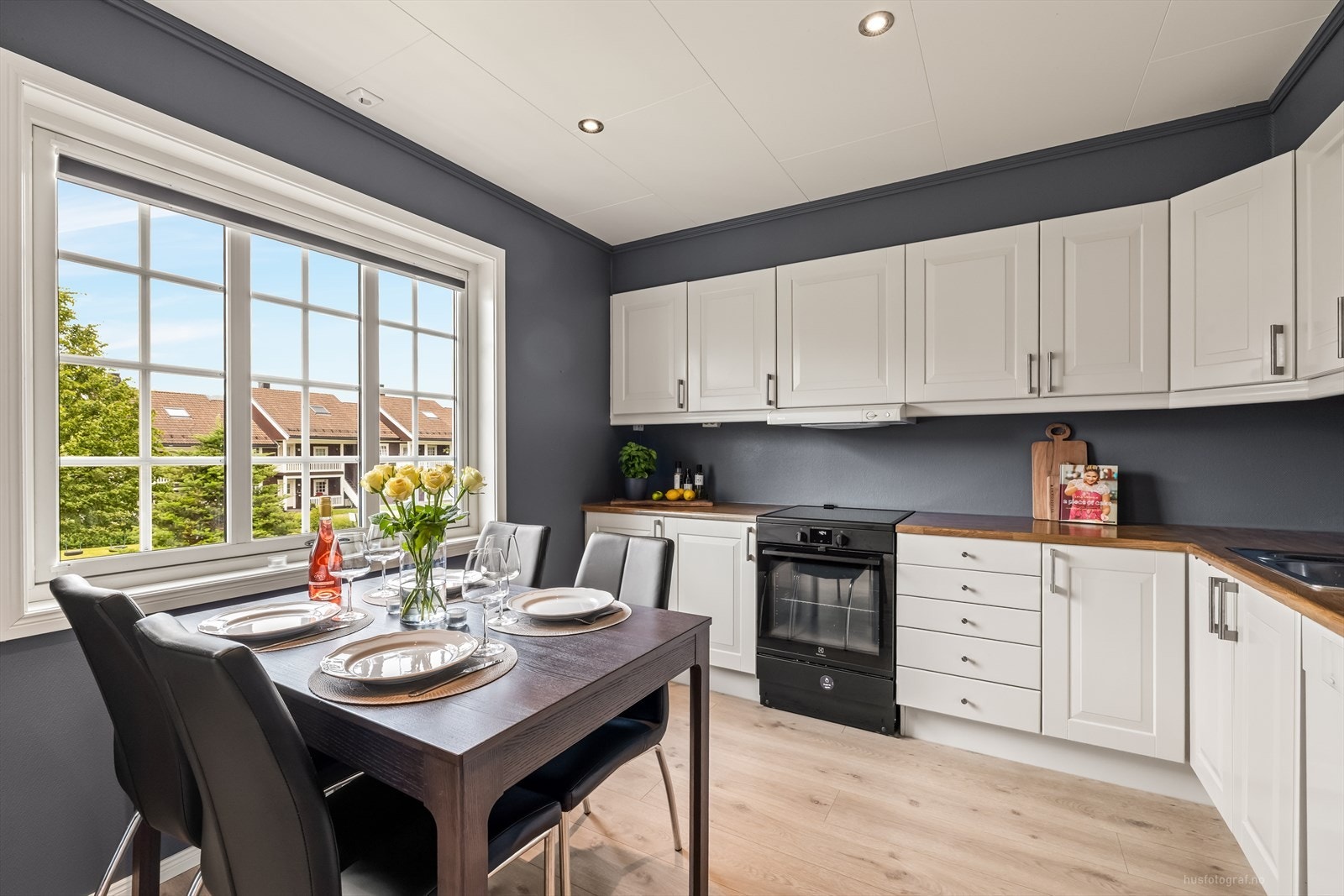 Klassisk og elegant kjøkkeninnredning med hvite profilerte fronter og benkeplate av laminat. Galleribilde