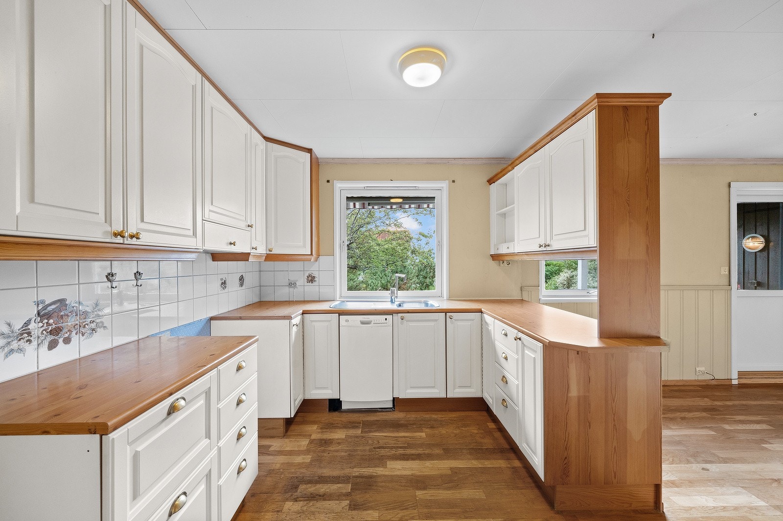 Kjøkkeninnredning med hvite profilerte fronter. Laminert benkeplate med nedfelt benkebeslag med oppvaskkum og 1-greps blandebatteri. Galleribilde