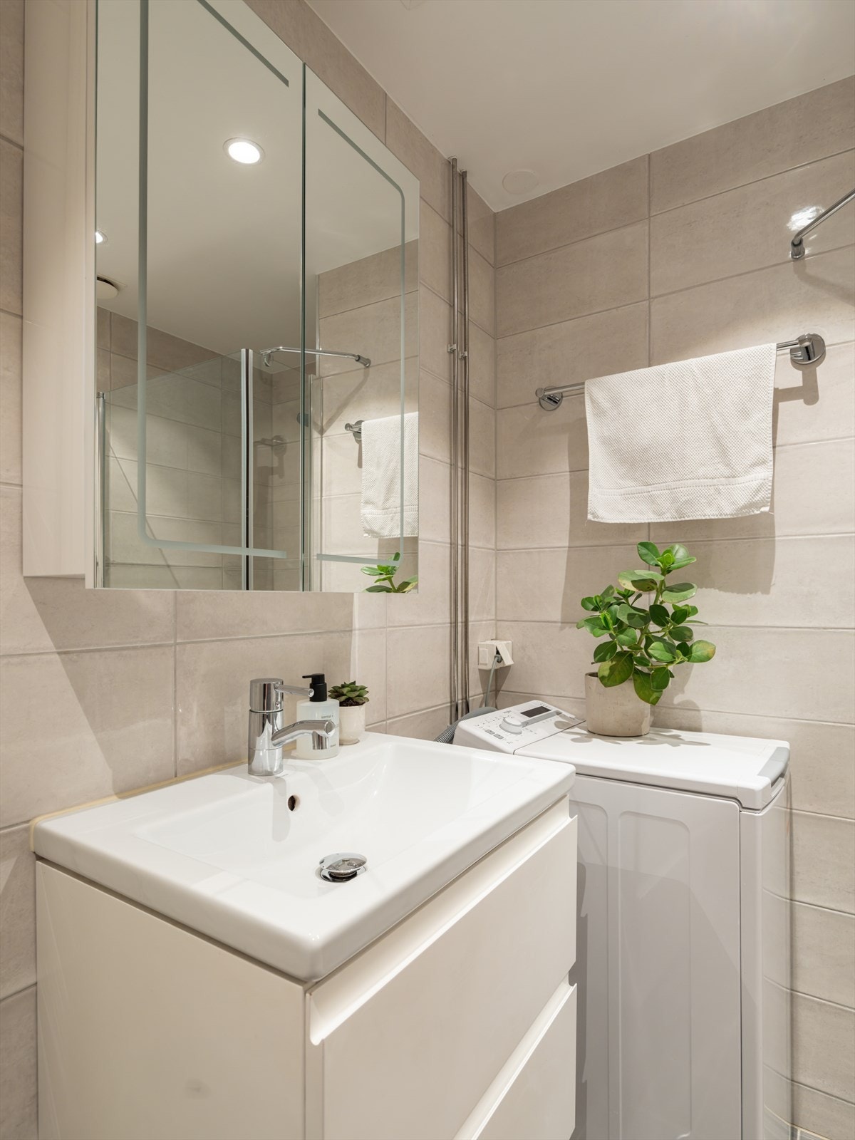 Badet er innredet med servant i skuffeseksjon og speilskap for oppbevaring. Opplegg for vaskemaskin. Galleribilde