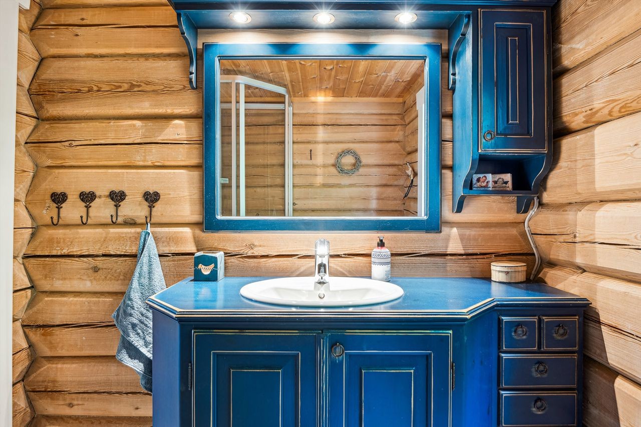 Badet har særpreg med blå sjarmerende innredning, servant med underskap og autentiske tømmervegger. Vannpumpe og bereder er plassert i underskapene Galleribilde