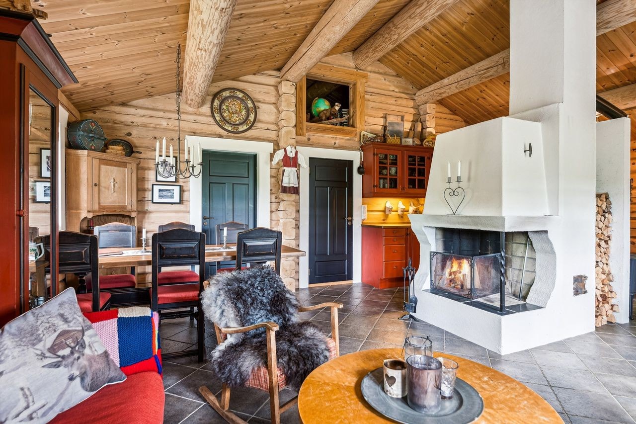 Stue med åpen peis, synlige takåser og lune tømmervegger for ekte hytteatmosfære. Galleribilde