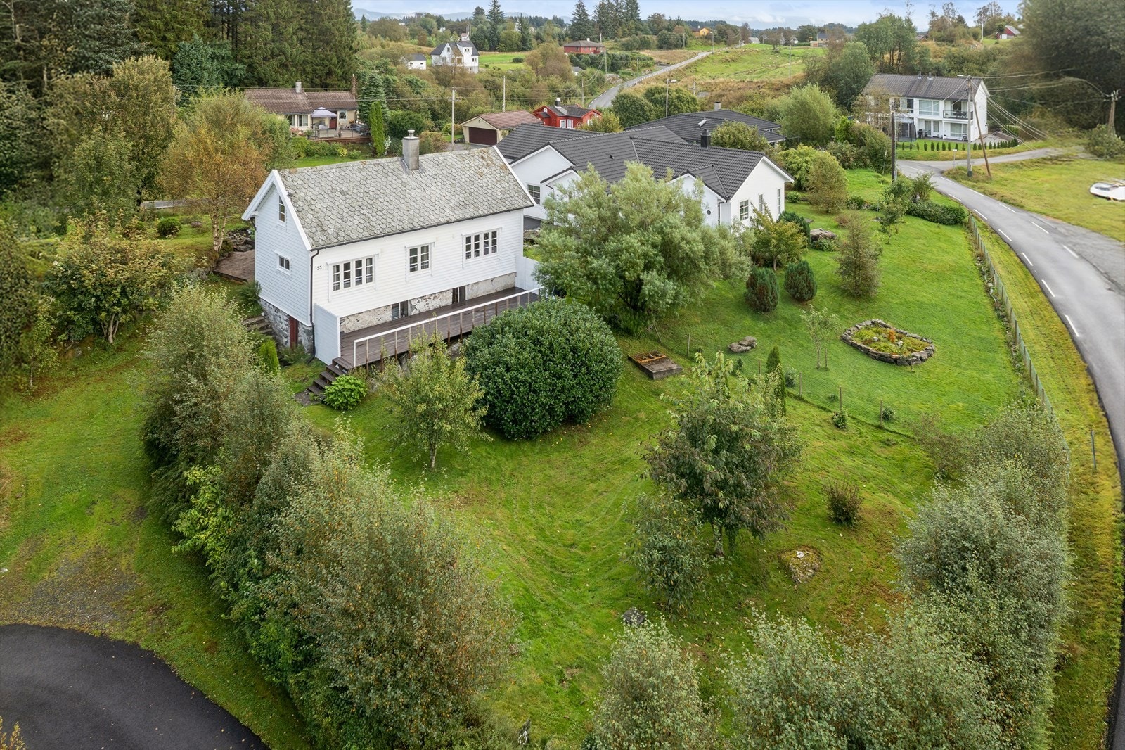 Hagen er pent opparbeidet med plen, terrasseplatting, trapper i betong, kantmur, bed, grøntareal og beplantet med både frukt trær og bærbusker Galleribilde