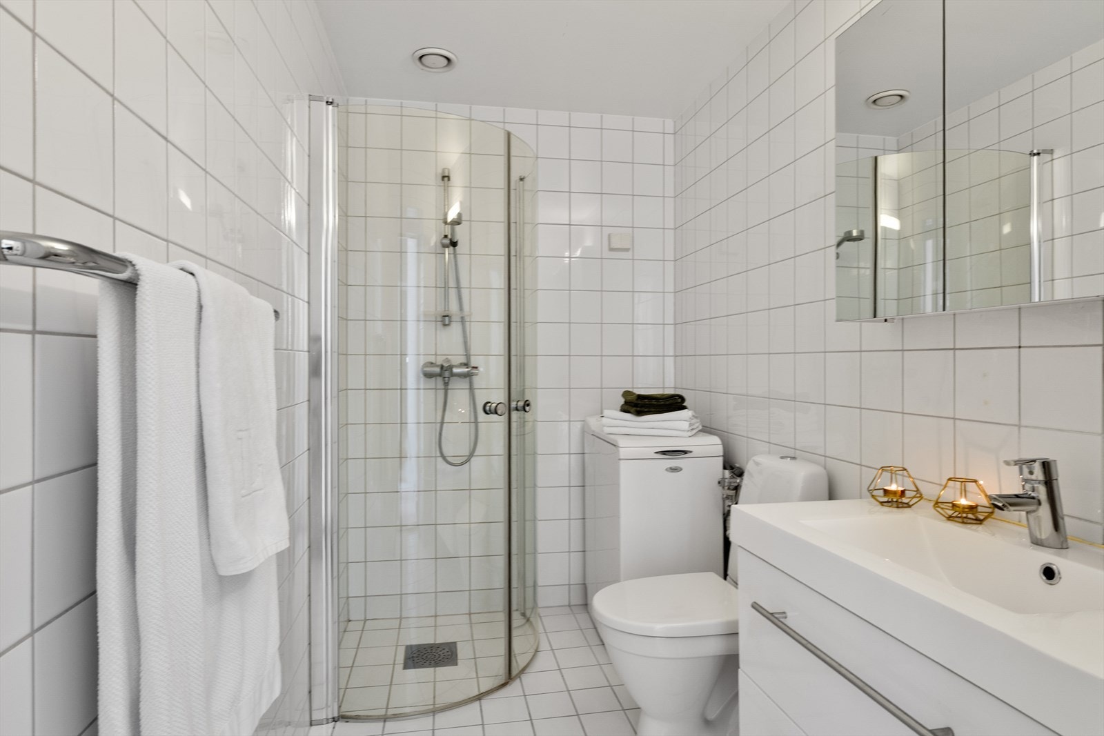 Badet er utstyrt med dusjhjørne, innfellbare dusjdører, opplegg for vaskemaskin, servant, servantskap og wc Galleribilde