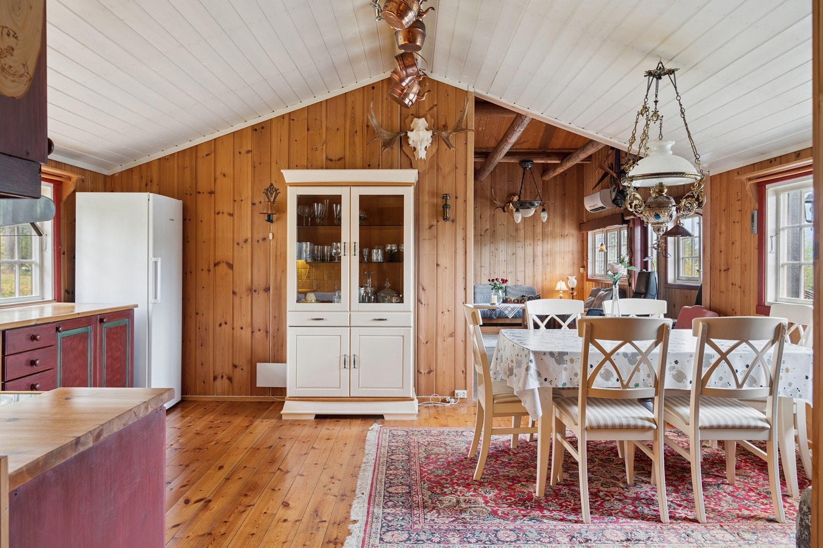 God takhøyde i flere rom, og gjennomgående vegger me dtrepanel samt tregulv. Spiseplassen binder sammen kjøkkenet og stuen, en sosial plass for felles måltider. Galleribilde