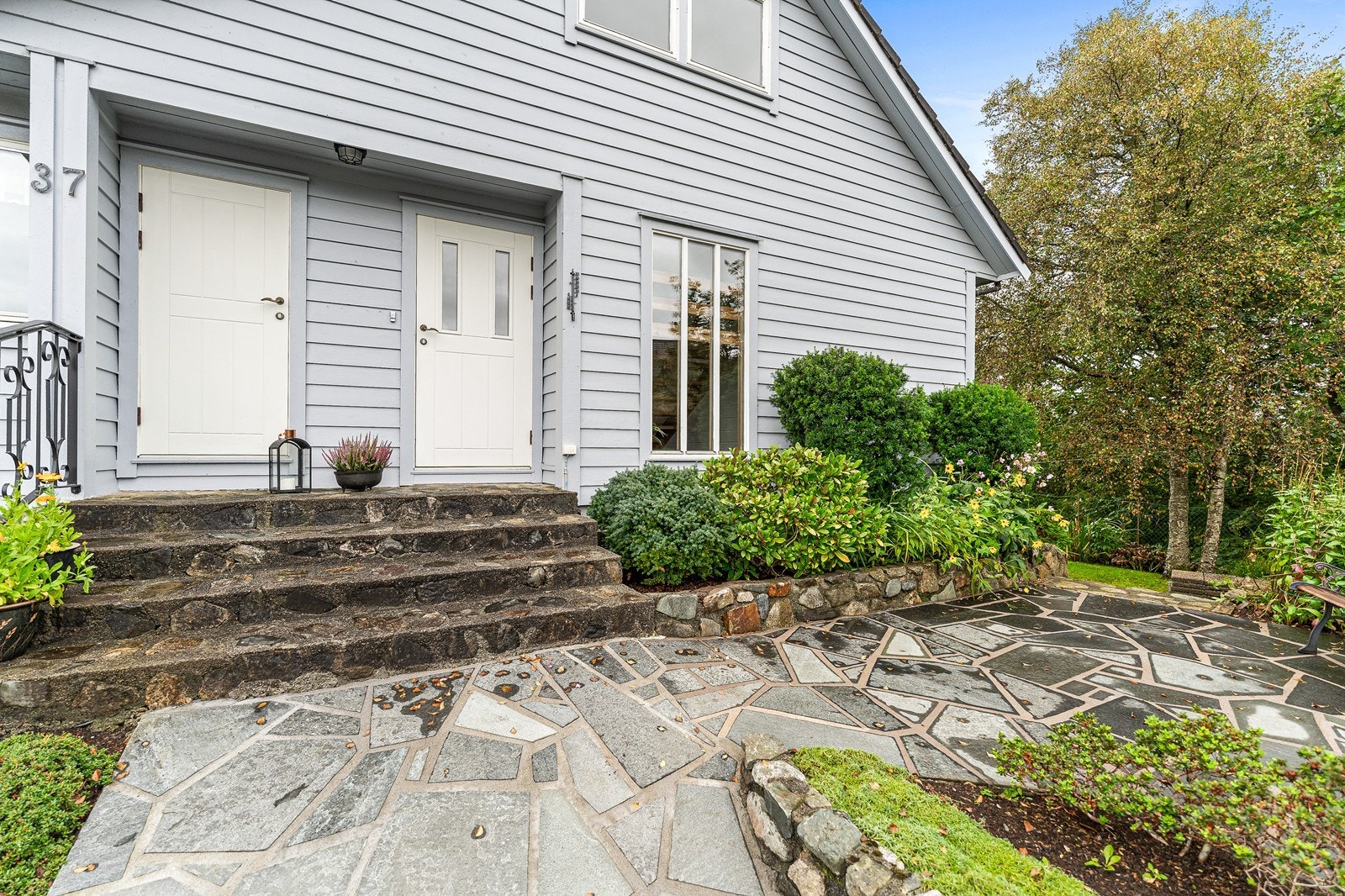 Boligen har et pent inngangsparti opparbeidet med murer og prydbusker. Galleribilde