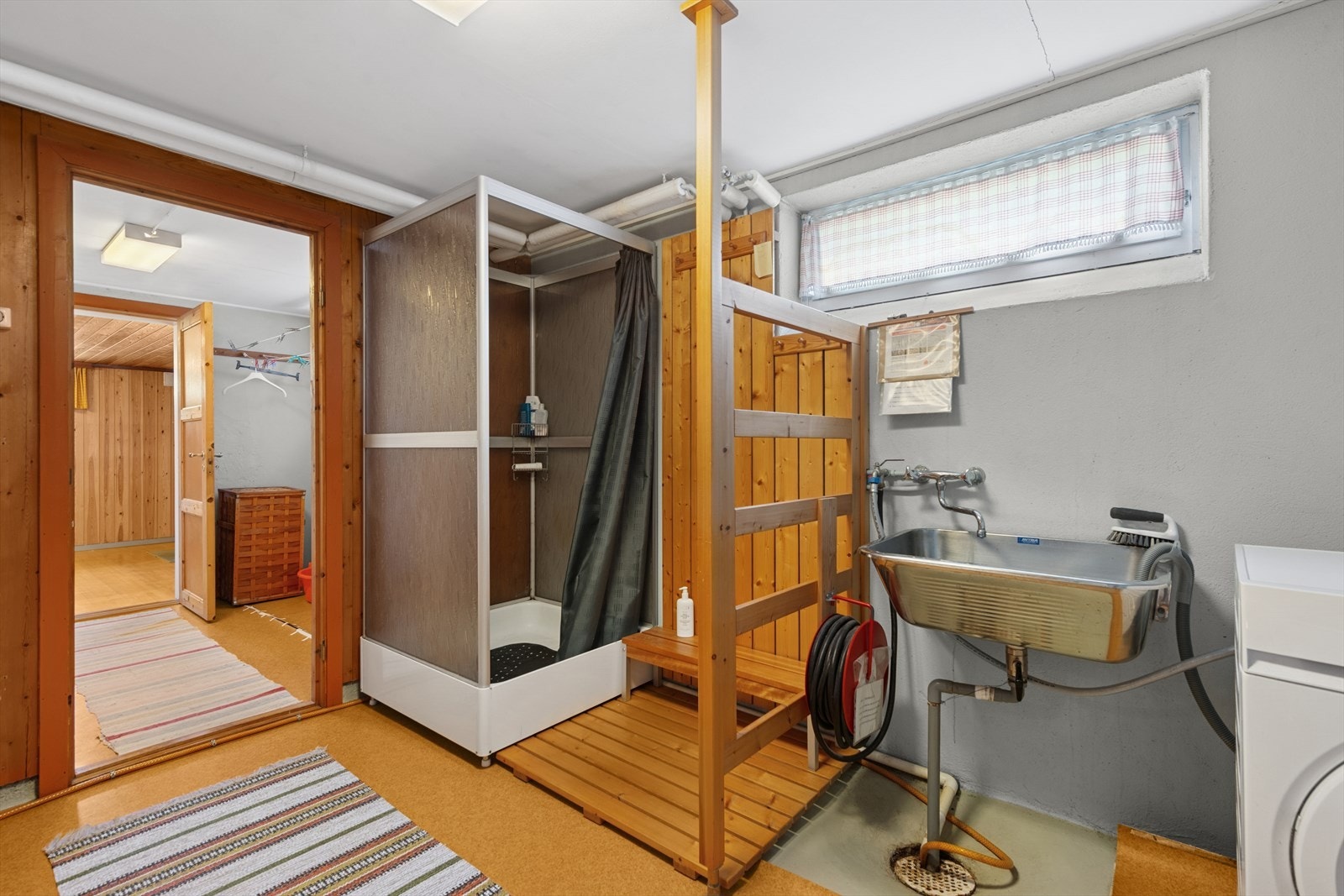 Badet i underetasjen er fra byggeår med malt mur og lakkert panel på veggene, og malt betong og pålagt gulvbelegg på gulvet. Galleribilde