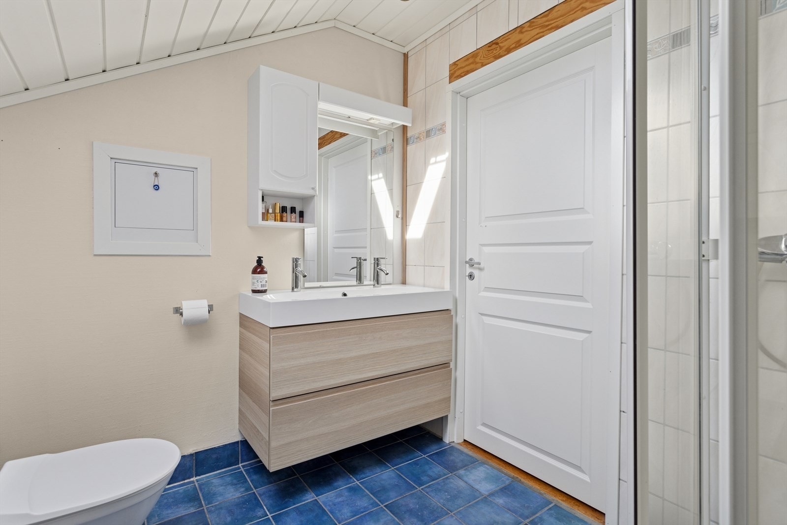 Baderommet har fliser på gulvet og fliser og malt strie på vegger. Galleribilde