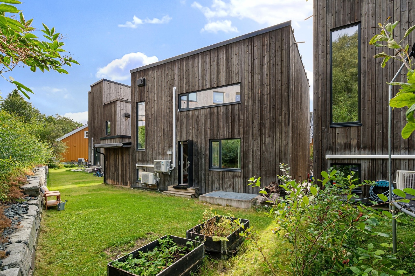 Flott uteområde med plen og beplantning, perfekt for sommerdager og hyggelige stunder utendørs. Galleribilde