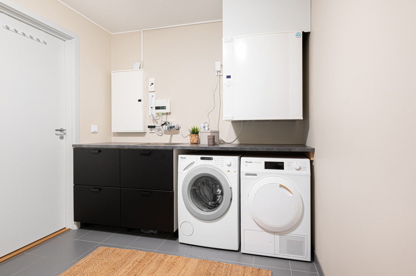 Praktisk vaskerom og teknisk rom med god benkeplass, opplegg for vaskemaskin og tørketrommel. Galleribilde