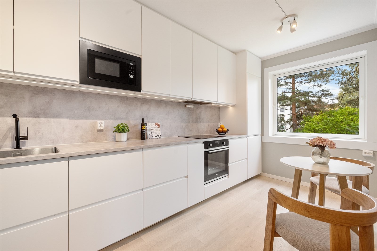 Pent og funksjonelt kjøkken med innredning fra IKEA med glatte fronter og laminert benkeplate med oppvaskkum og induksjonstopp. Galleribilde