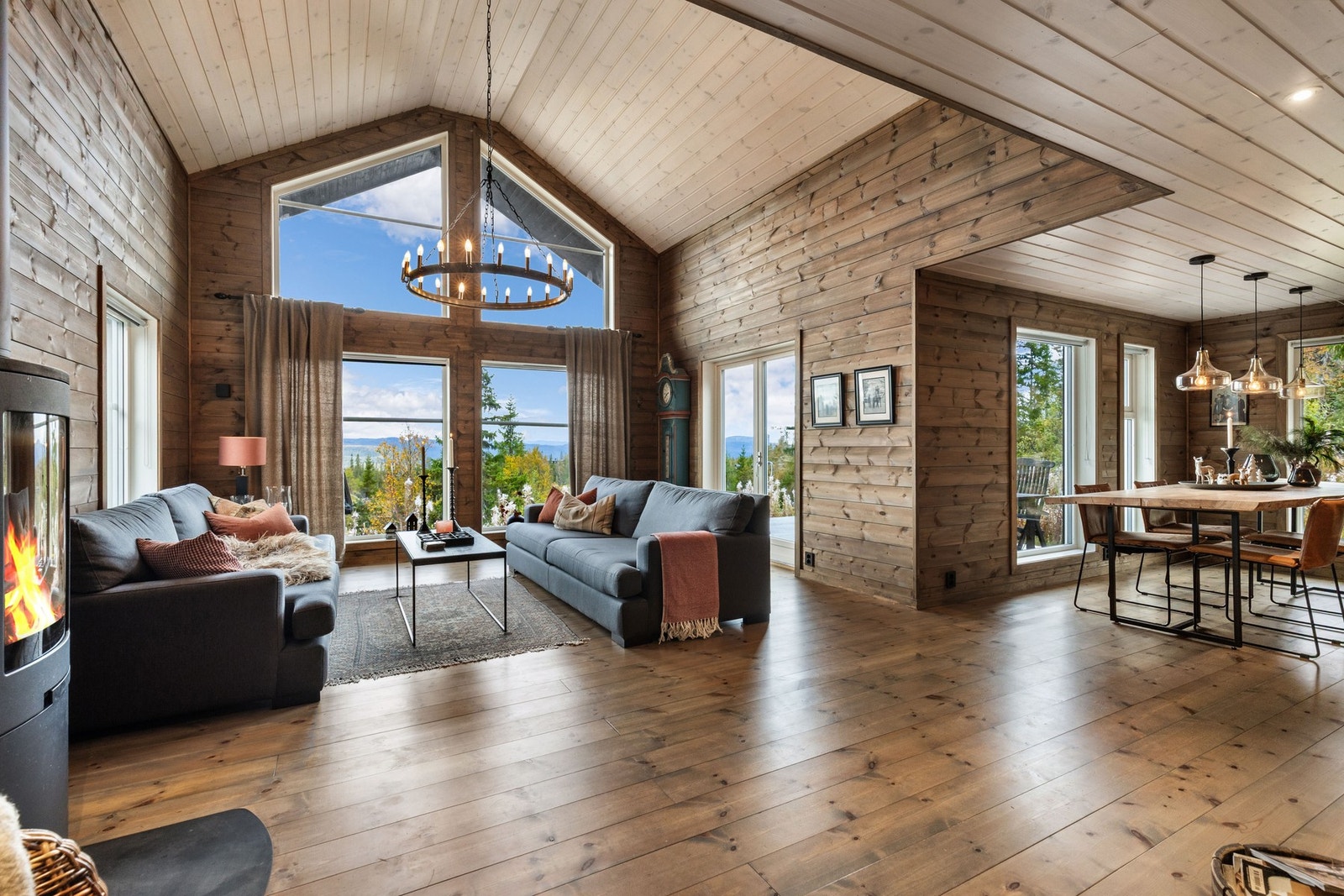 Den åpne løsningen mot kjøkken og spisestue gir et luftig og sosialt oppholdsrom, og vedovnen gir både varme og en lun atmosfære på kalde vinterdager Galleribilde