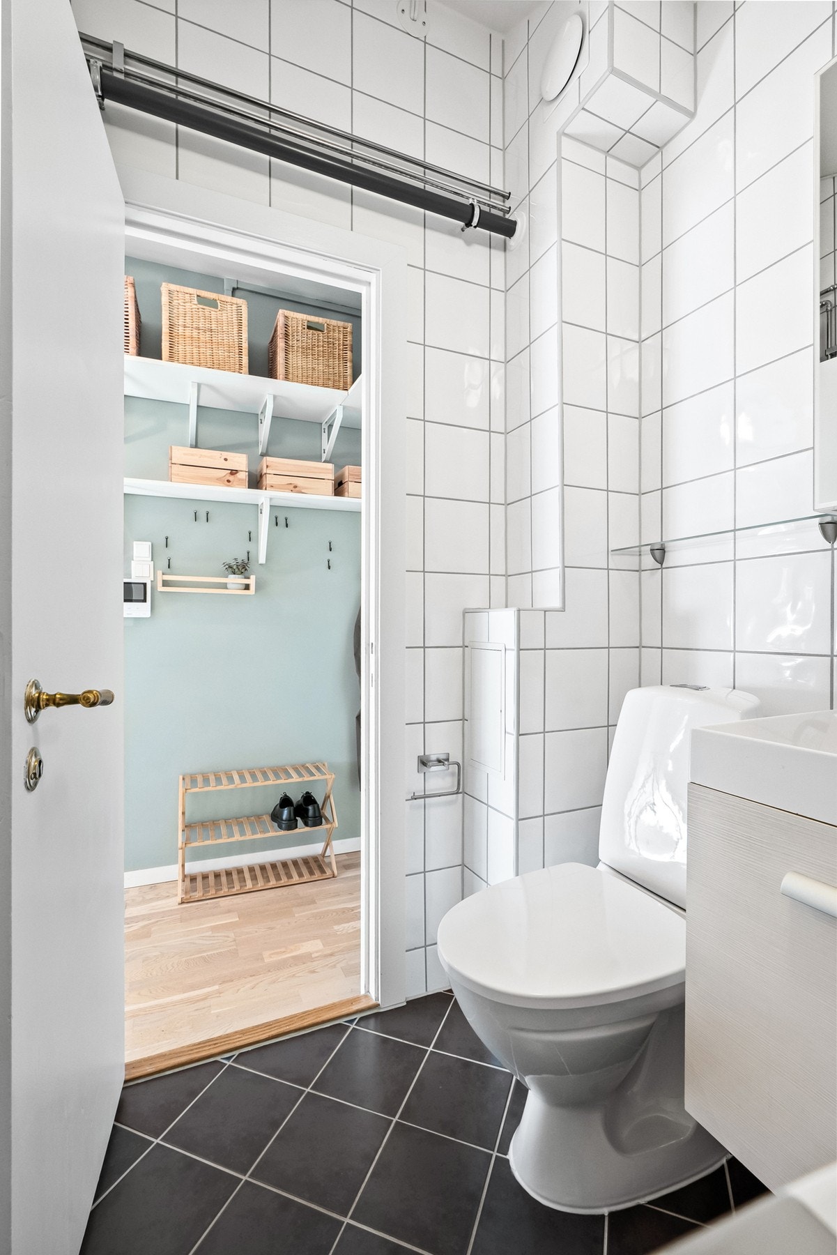 Videre har badet et toalett, opplegg for vaskemaskin og et dusjhjørne med veggmontert dusjarmatur bak forheng. Galleribilde