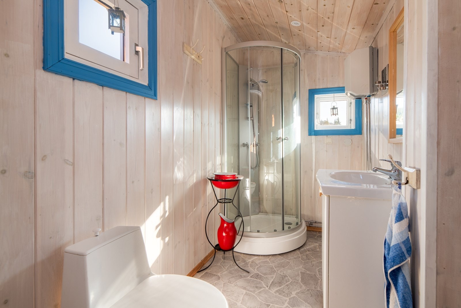Det er etablert baderom med enkel standard og utvendig adkomst fra terrassen. Her er det baderomsinnredning med servant, dusjkabinett og snurretoalett. Liten varmtvannsbereder på vegg. Galleribilde
