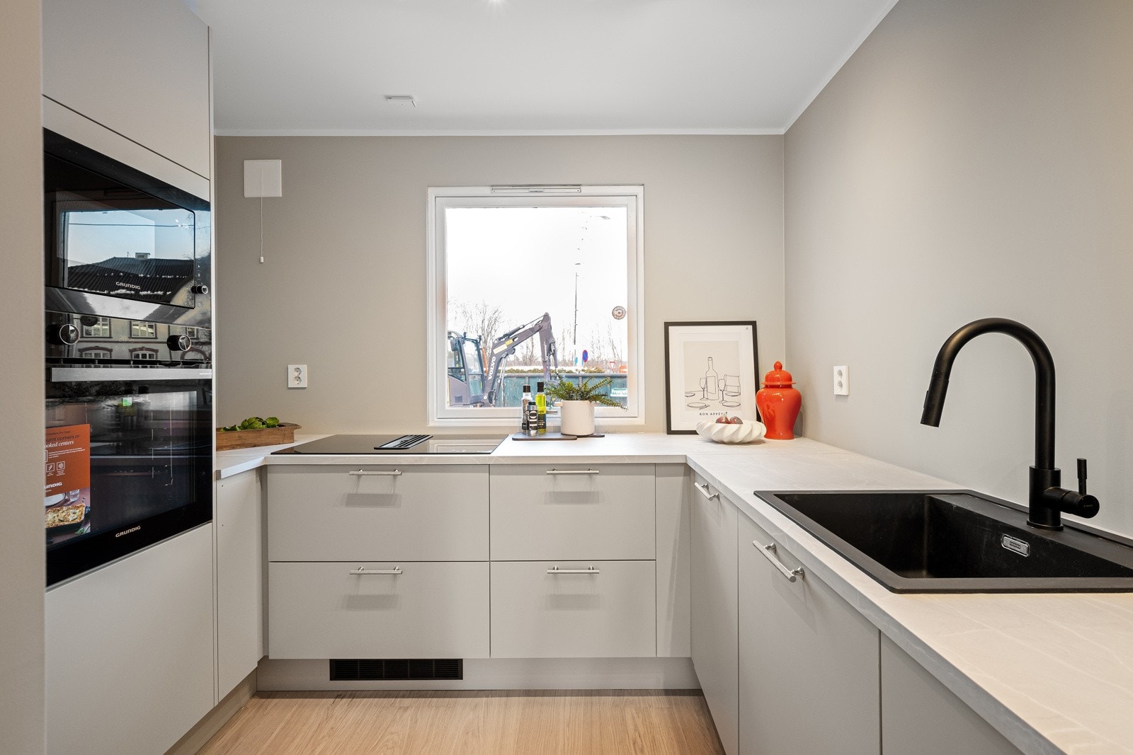 Kjøkkenet har en stilren innredning med glatte, folierte fronter og en slitesterk laminatbenkeplate med nedfelt kum i kompositt/plast Galleribilde