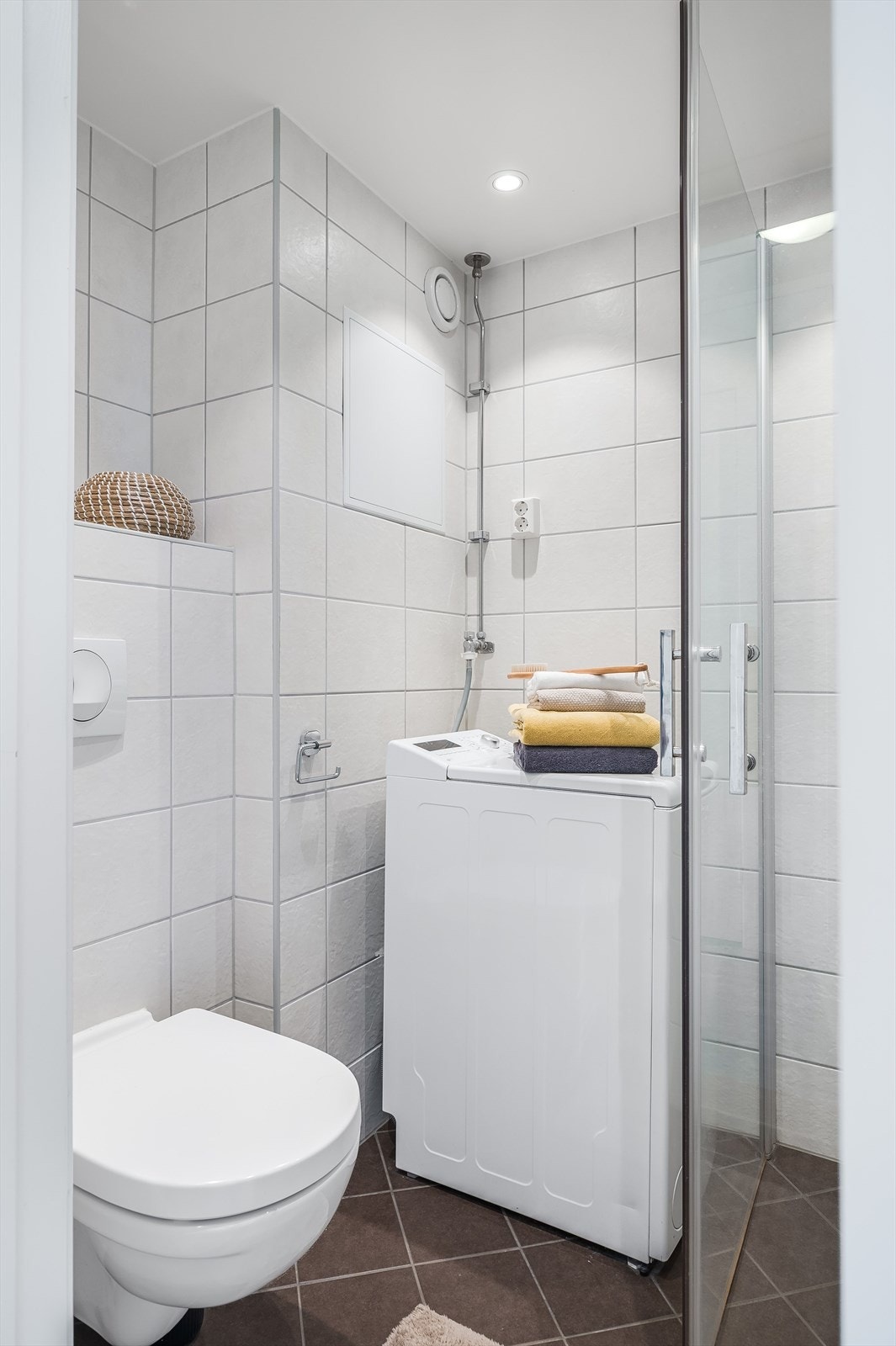 Baderommet har brune fliser på gulv med gulvvarme, hvite fliser på veggene, downlights i himlingen og mekanisk avtrekk. Galleribilde