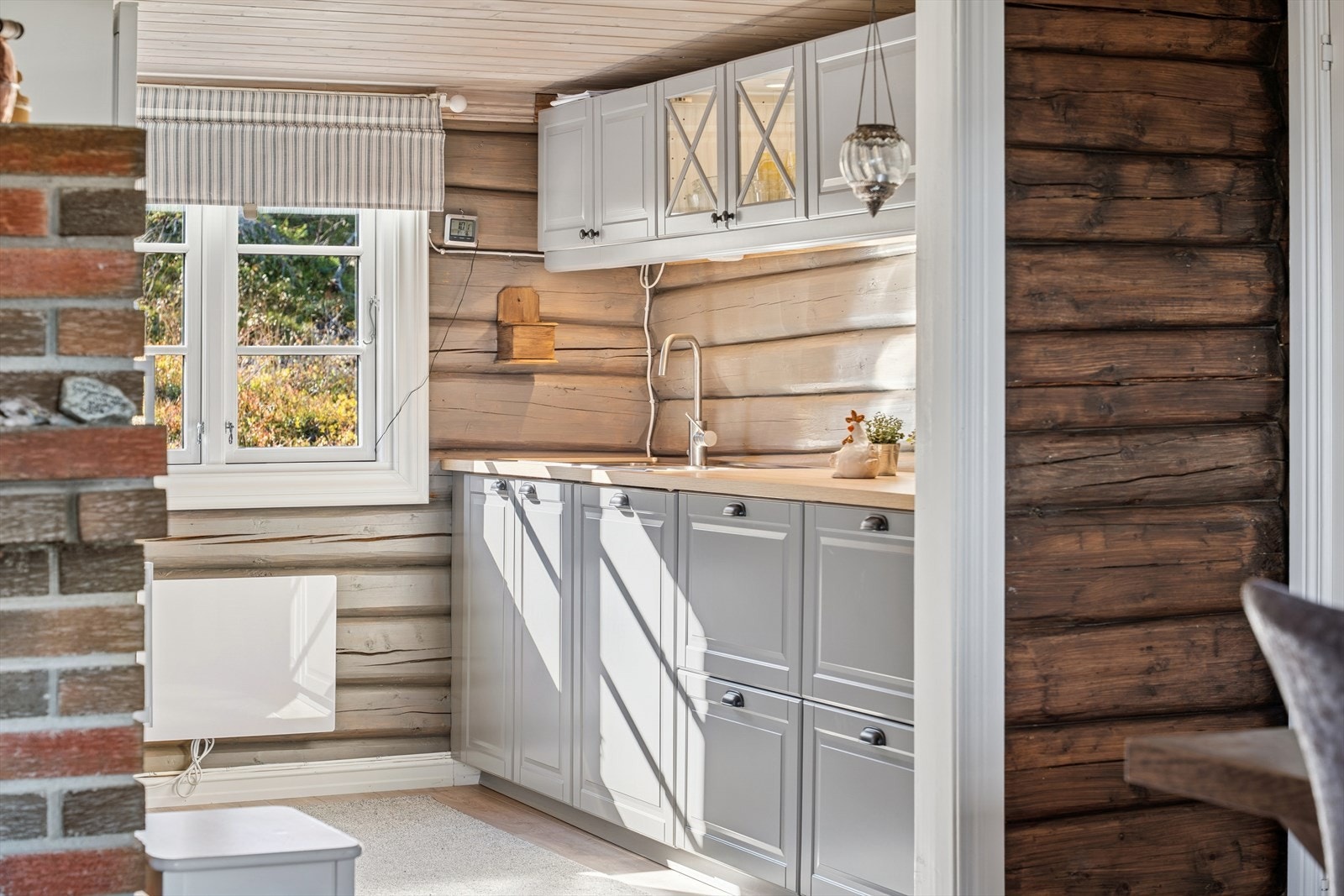 Kjøkkenet er innredet med lyse, profilerte fronter og overskap med glassfelt. Benkeplaten er i laminat med nedfelt oppvaskkum i stål. Galleribilde