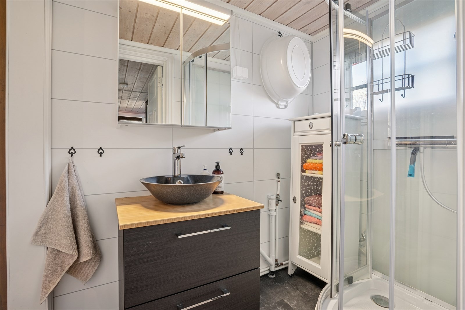 Badet har vinylfliser på gulv, baderomsplater på vegger og trepanel i himling. Innredningen består av servantskap med benkeplate og servant, samt dusjkabinett. Det er ikke innlagt vann i hytta, badet er klargjort for dette, men det må søkes om til kommune Galleribilde