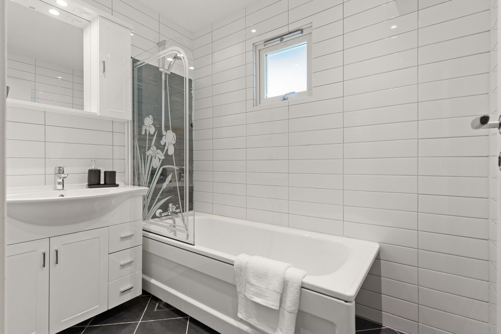 Badet ble renovert i 2012 og har fliser på vegger og gulv, elektriske varmekabler og innfelt belysning i taket. Her finnes servantskap med heldekkende servant og badekar med dusjvegg i glass. Galleribilde