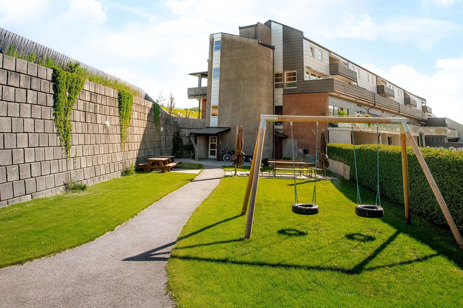 Flott opparbeidet grøntareal ved inngangen, med plen, beplantning og sittegrupper for felles bruk. Her er det også satt opp huskestativ for barna. Galleribilde