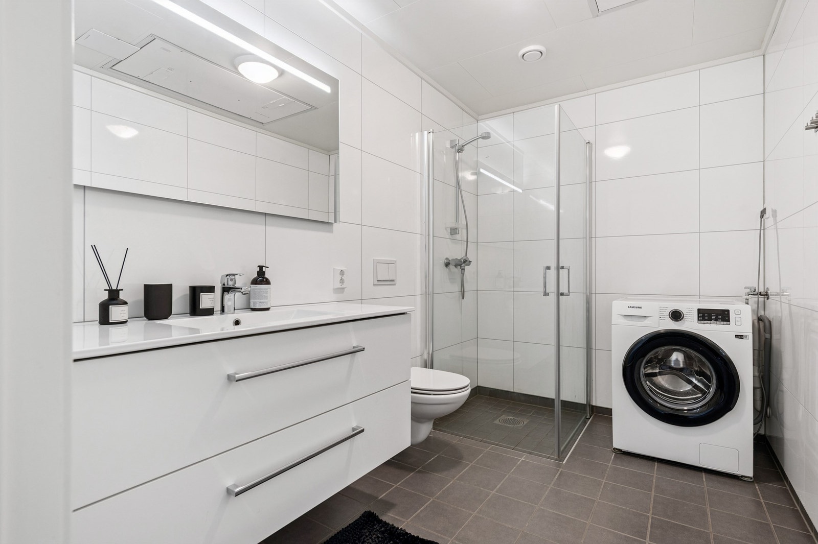 Badet er helfliset med varme i gulvet, dusjhjørne, vegghengt toalett og opplegg for vaskemaskin. Galleribilde