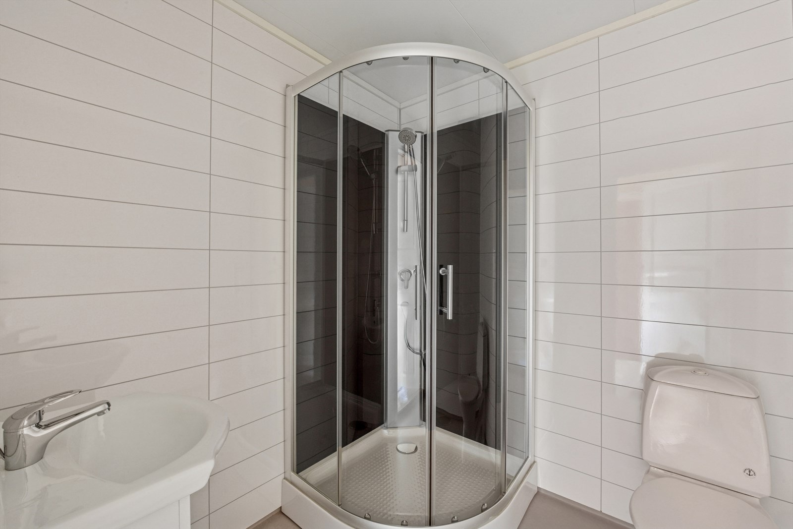 Baderommet i underetasjen er innredet med dusjkabinett, gulvmontert toalett og servant. Galleribilde