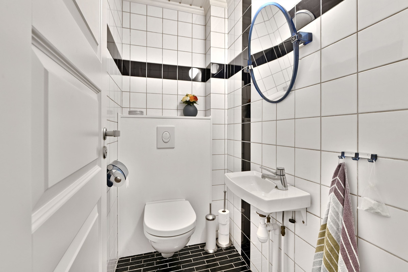 WC-rom - flislagt gulv og vegger - vegghengt servant, speil og belysning over servant og vegghengt toalett Galleribilde