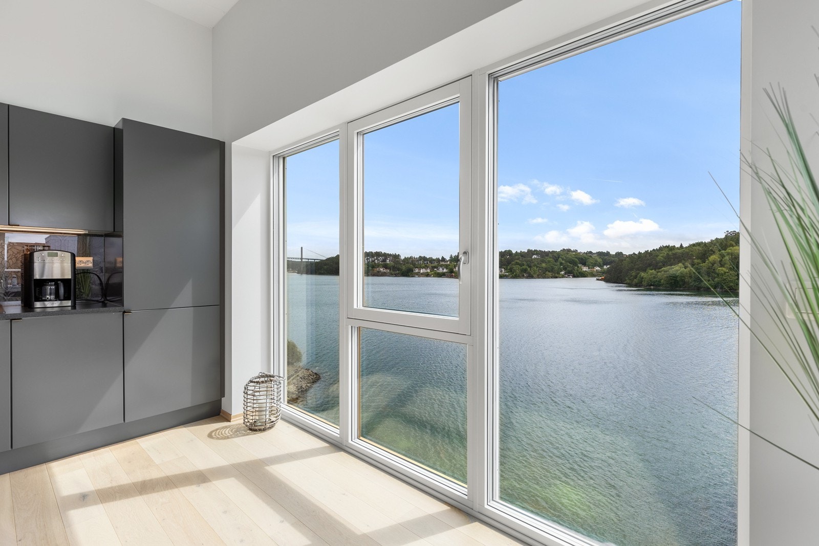 Kjøkkenet har vinduer fra gulv til tak for maksimal utnyttelse av utsikten og innslipp av naturlig lys. Her er det yrende båtliv å følge med på sommerstid. Galleribilde