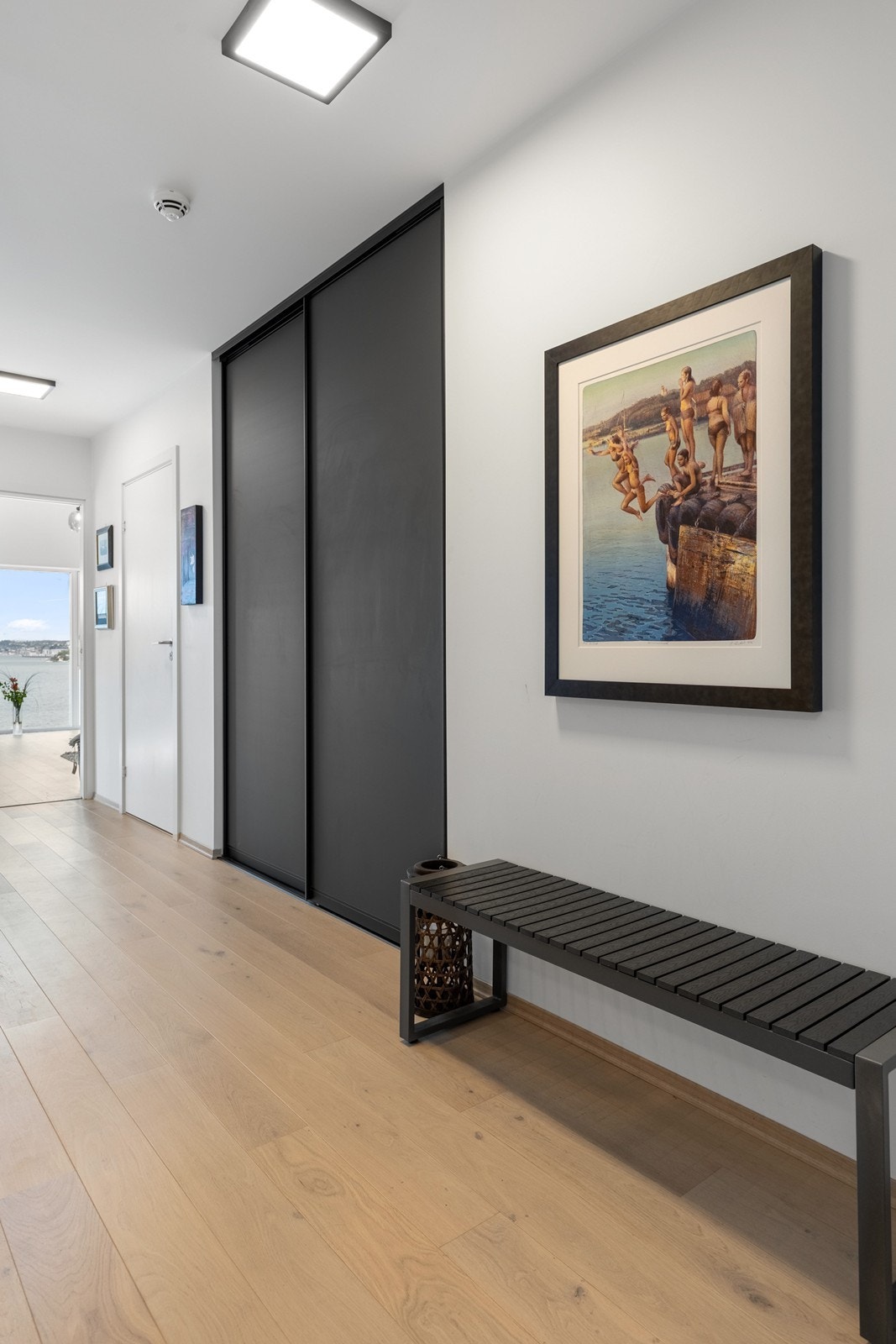 Romslig entrè med skyvedørsgarderobe fra Amiga. Når man kommer inn i entrèen ser man rett gjennom leiligheten og videre til sjøen og inn mot byen Galleribilde