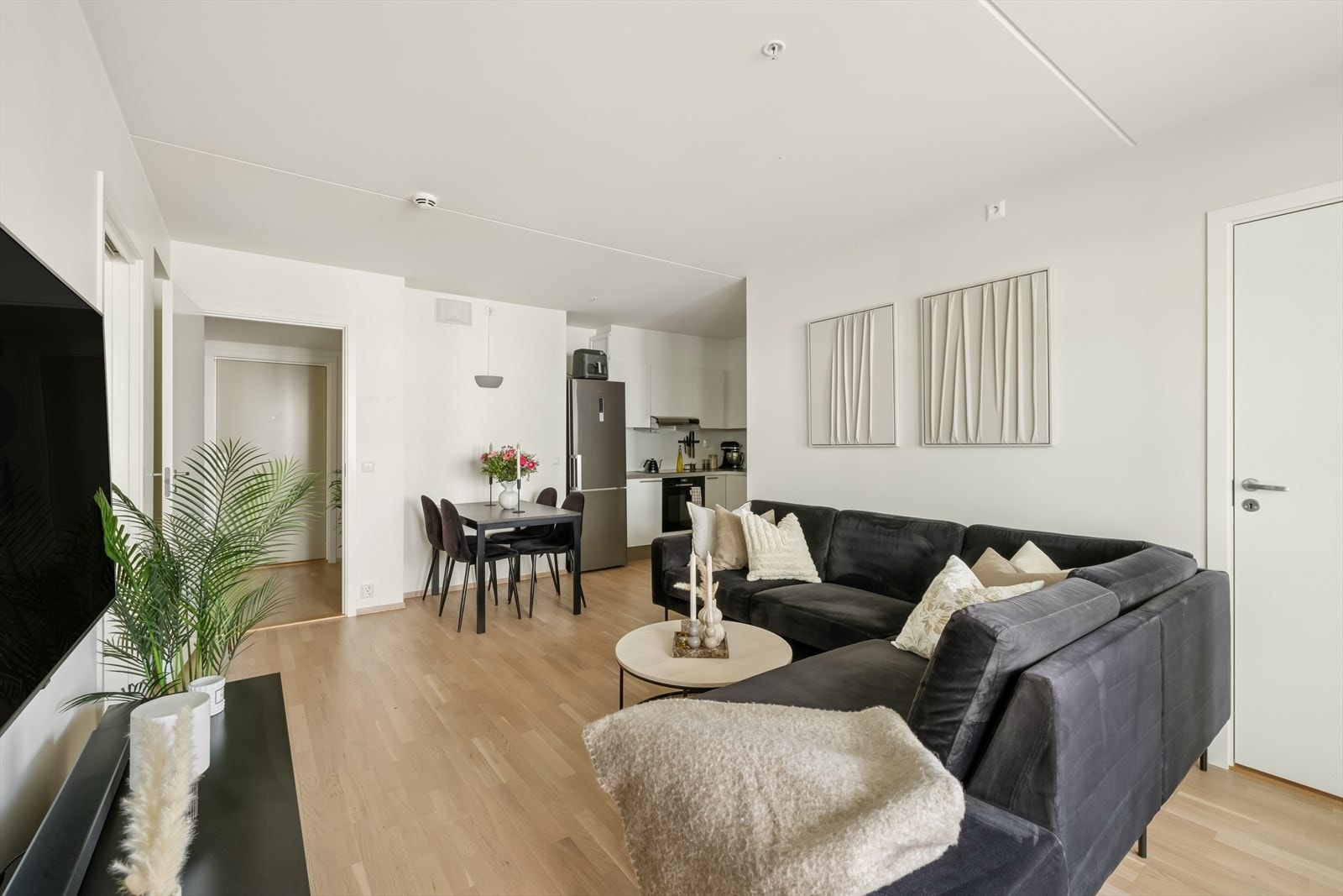 Stue og kjøkken i åpen løsning hvor kjøkkenet ligger tilbaketrukket i en nisje. Galleribilde