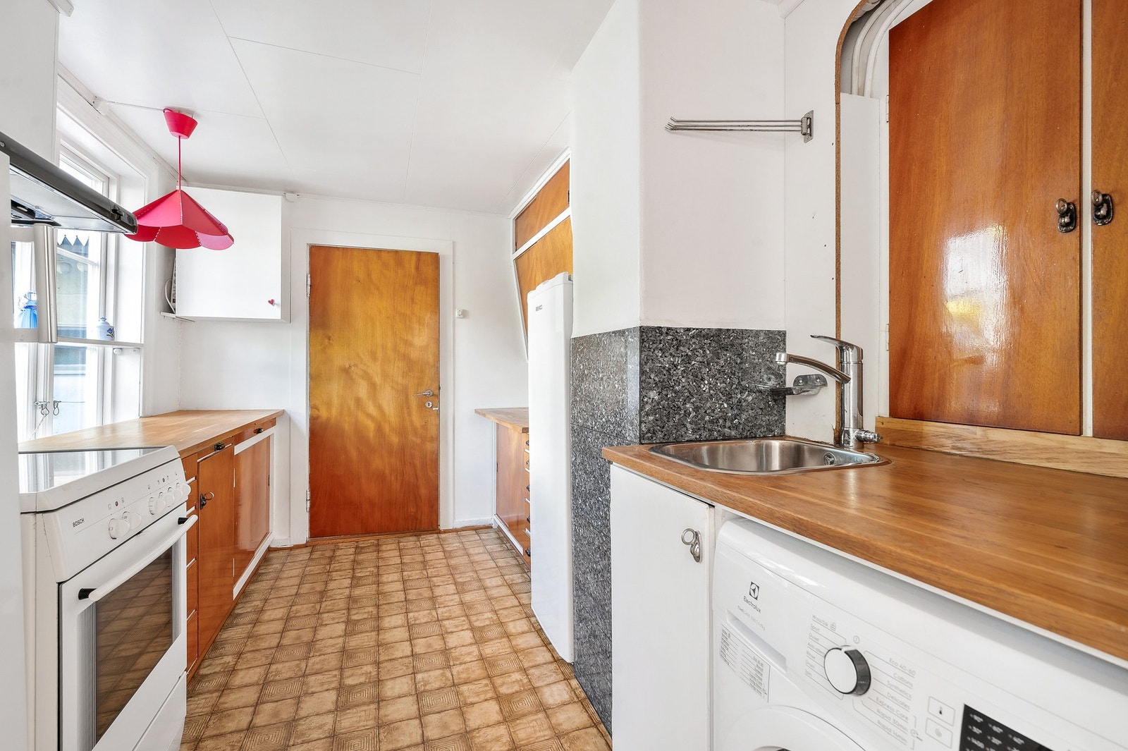 Eldre kjøkken med god skap- og benkeplass. Det er opplegg for vaskemaskin på kjøkkenet. Galleribilde