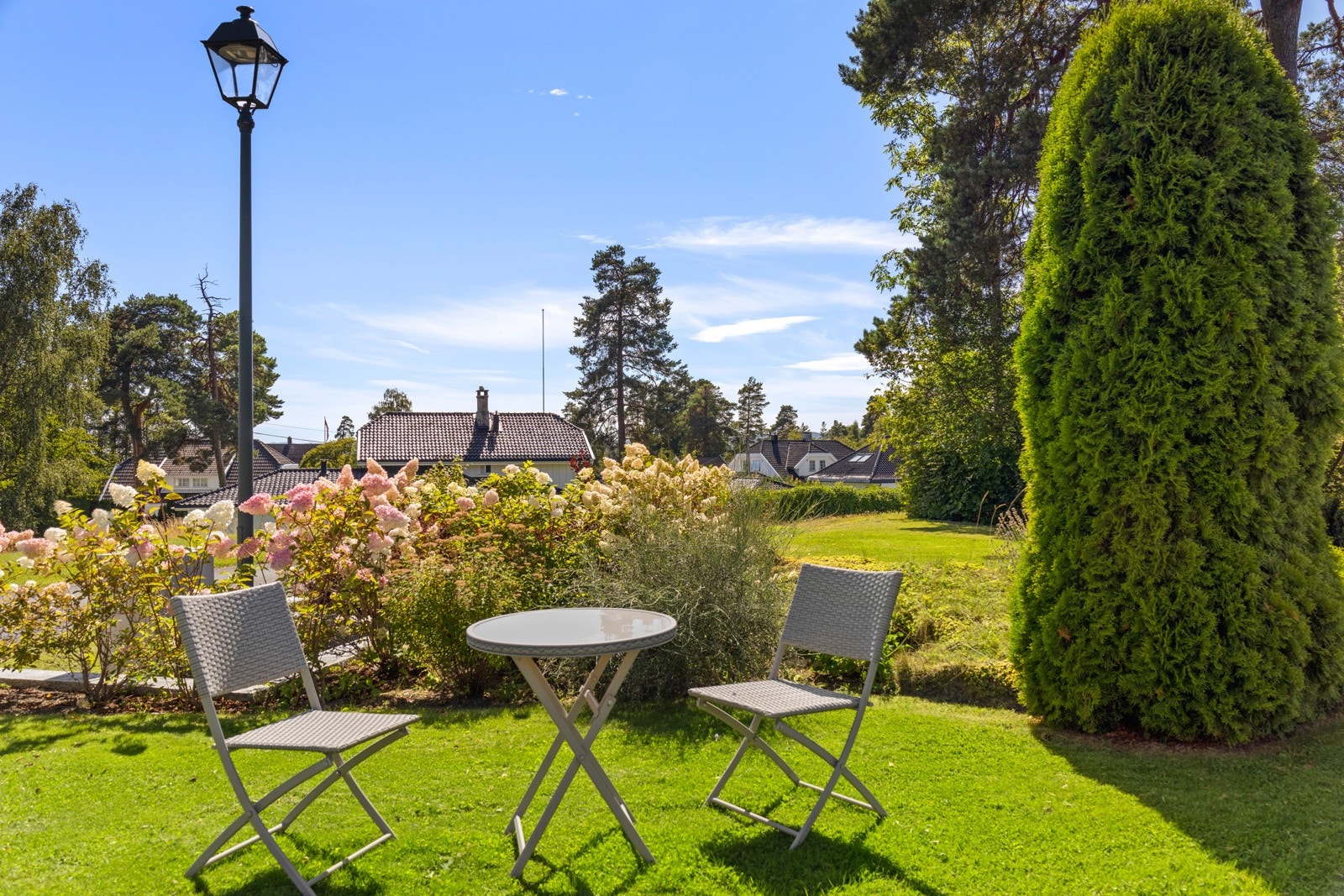Parkmessig og flott opparbeidet hage, hovedsakelig flat med stor gressplen og rikelig med beplantning og bed Galleribilde