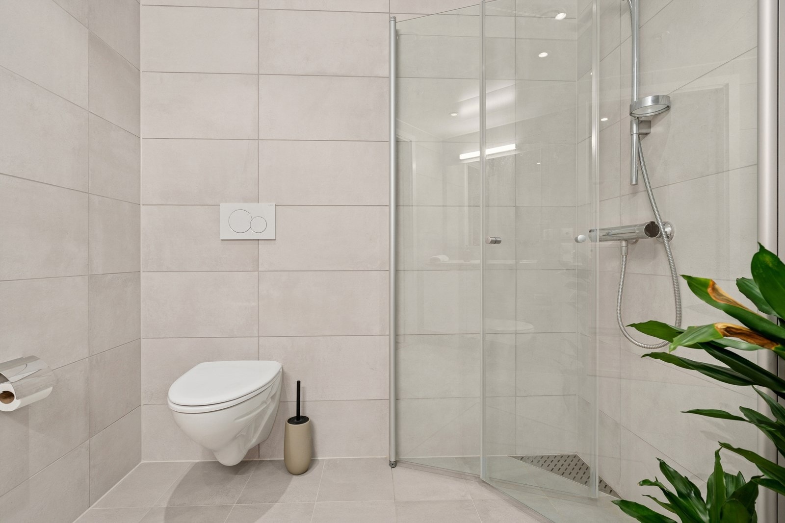 Badet er utstyrt med vegghengt toalett, dusjhjørne m/innfellbare glassdører, baderomsinnredning og opplegg for vaskemaskin Galleribilde